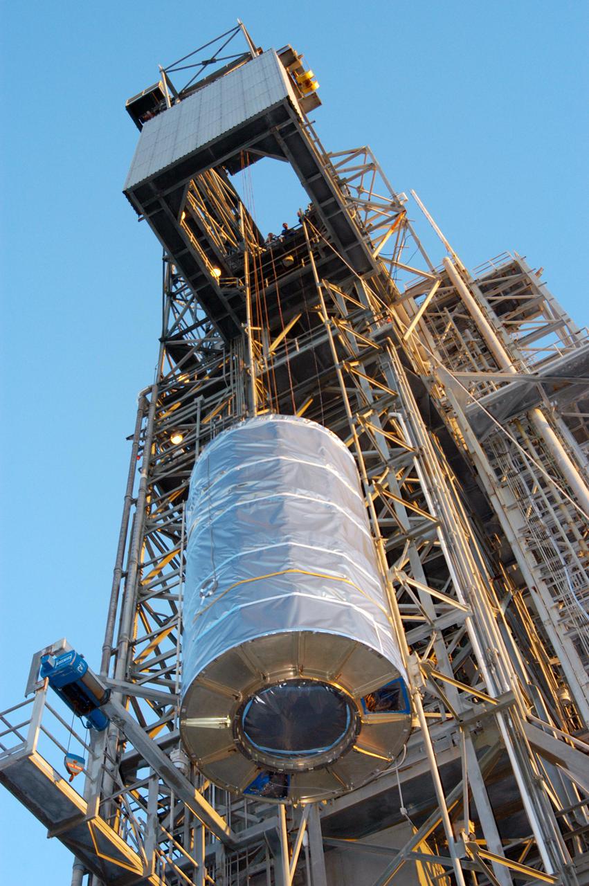 KENNEDY SPACE CENTER, FLA. - At Launch Pad 17-A on Cape Canaveral Air Force Station in Florida, the wrapped spacecraft Swift is slowly lifted up the mobile service tower for mating to the Boeing Delta II launch vehicle waiting there. Swift is scheduled to launch Nov. 17. The liftoff aboard a Boeing Delta II rocket is targeted at the opening of a one-hour launch window beginning at 12:09 p.m. EST. A first-of-its-kind multi-wavelength observatory dedicated to the study of gamma-ray burst (GRB) science, Swift’s three instruments will work together to observe GRBs and afterglows in the gamma ray, X-ray, ultraviolet and optical wavebands. Gamma-ray bursts are distant, yet fleeting explosions that appear to signal the births of black holes.