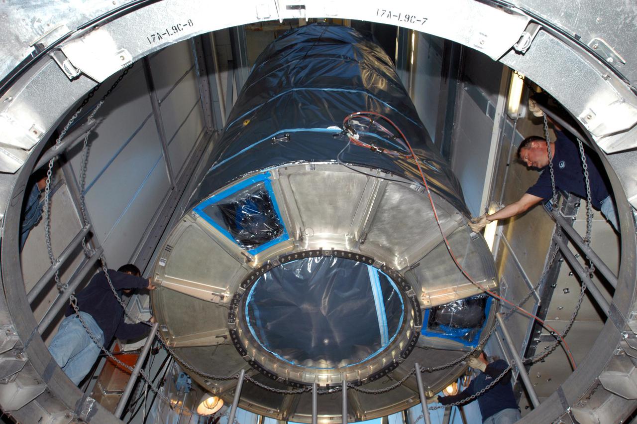 KENNEDY SPACE CENTER, FLA. - In the mobile service tower on Launch Pad 17-A, Cape Canaveral Air Force Station, Boeing technicians help guide the Swift spacecraft as it is lowered toward the Boeing Delta II launch vehicle for mating. Swift is scheduled to launch Nov. 17. The liftoff aboard a Boeing Delta II rocket is targeted at the opening of a one-hour launch window beginning at 12:09 p.m. EST. A first-of-its-kind multi-wavelength observatory dedicated to the study of gamma-ray burst (GRB) science, Swift’s three instruments will work together to observe GRBs and afterglows in the gamma ray, X-ray, ultraviolet and optical wavebands. Gamma-ray bursts are distant, yet fleeting explosions that appear to signal the births of black holes.