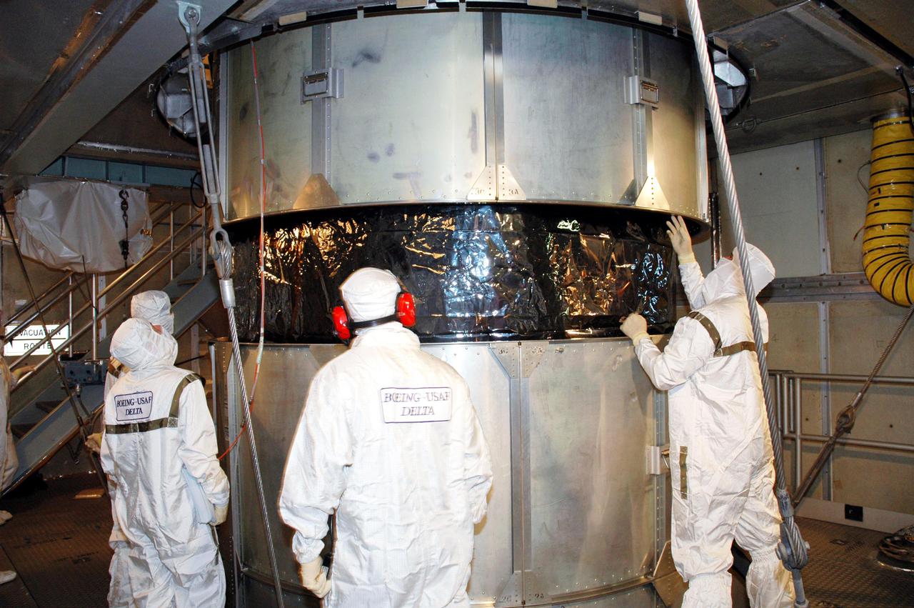 KENNEDY SPACE CENTER, FLA. -  Inside the mobile service tower on Launch Pad 17-A , Cape Canaveral Air Force Station, Fla., Boeing technicians observe the lifting of the transport canister surrounding the Swift spacecraft. A first-of-its-kind multi-wavelength observatory dedicated to the study of gamma-ray burst (GRB) science, Swift’s three instruments will work together to observe GRBs and afterglows in the gamma ray, X-ray, ultraviolet and optical wavebands. It is expected to observe more than 200 gamma-ray bursts - the most comprehensive study of GRB afterglows to date - during its 2-year mission.  Gamma-ray bursts are distant, yet fleeting explosions that appear to signal the births of black holes.  Swift is scheduled to launch aboard a Boeing Delta II rocket at the opening of a one-hour launch window beginning at 12:09 p.m. EST Nov. 17.