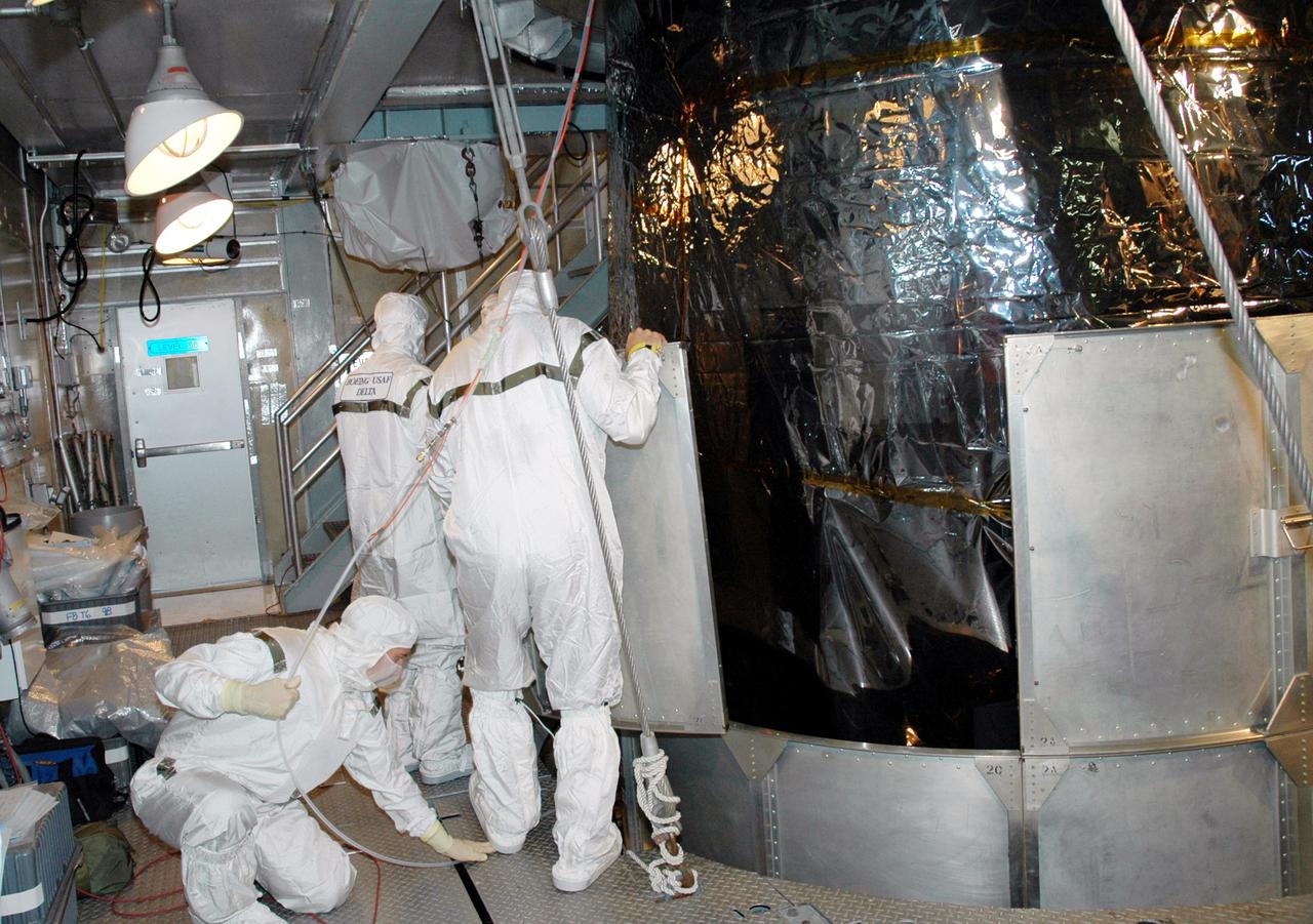 KENNEDY SPACE CENTER, FLA. -  Inside the mobile service tower on Launch Pad 17-A , Cape Canaveral Air Force Station, Fla., Boeing technicians remove the lower portion of the transport canister from the Swift spacecraft. A first-of-its-kind multi-wavelength observatory dedicated to the study of gamma-ray burst (GRB) science, Swift’s three instruments will work together to observe GRBs and afterglows in the gamma ray, X-ray, ultraviolet and optical wavebands. It is expected to observe more than 200 gamma-ray bursts - the most comprehensive study of GRB afterglows to date - during its 2-year mission.  Gamma-ray bursts are distant, yet fleeting explosions that appear to signal the births of black holes.  Swift is scheduled to launch aboard a Boeing Delta II rocket at the opening of a one-hour launch window beginning at 12:09 p.m. EST Nov. 17.