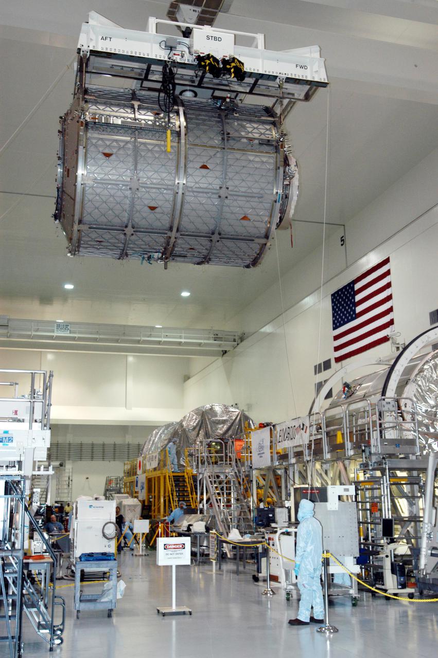 KENNEDY SPACE CENTER, FLA. -  In the Space Station Processing Facility, workers watch the progress of the Multi-Purpose Logistics Module Leonardo as it moves across the building to the Cargo Element Work Stand that Raffaello recently vacated.  The payload canister was a temporary location during the switch. At right is the MPLM Raffaello, temporarily occupying the Element Rotation Stand formerly holding Leonardo.  Three MPLMs were built by the Italian Space Agency - Donatello, Leonardo and Raffaello - to serve as a reusable logistics carrier and primary delivery system to resupply and return cargo requiring a pressurized environment to the International Space Station.