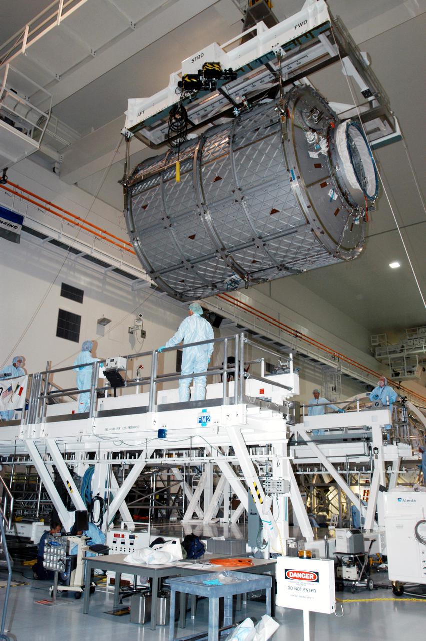 KENNEDY SPACE CENTER, FLA. -  In the Space Station Processing Facility, workers stand by as the Multi-Purpose Logistics Module Leonardo is lowered toward the Cargo Element Work Stand that Raffaello recently vacated.  The payload canister was a temporary location during the switch.  Three MPLMs were built by the Italian Space Agency - Donatello, Leonardo and Raffaello - to serve as a reusable logistics carrier and primary delivery system to resupply and return cargo requiring a pressurized environment to the International Space Station.