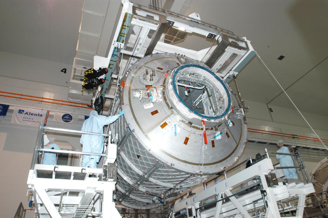KENNEDY SPACE CENTER, FLA. -  In the Space Station Processing Facility, workers guide the Multi-Purpose Logistics Module Leonardo as it is lowered toward the Cargo Element Work Stand that Raffaello recently vacated.  The payload canister was a temporary location during the switch.  Three MPLMs were built by the Italian Space Agency - Donatello, Leonardo and Raffaello - to serve as a reusable logistics carrier and primary delivery system to resupply and return cargo requiring a pressurized environment to the International Space Station.