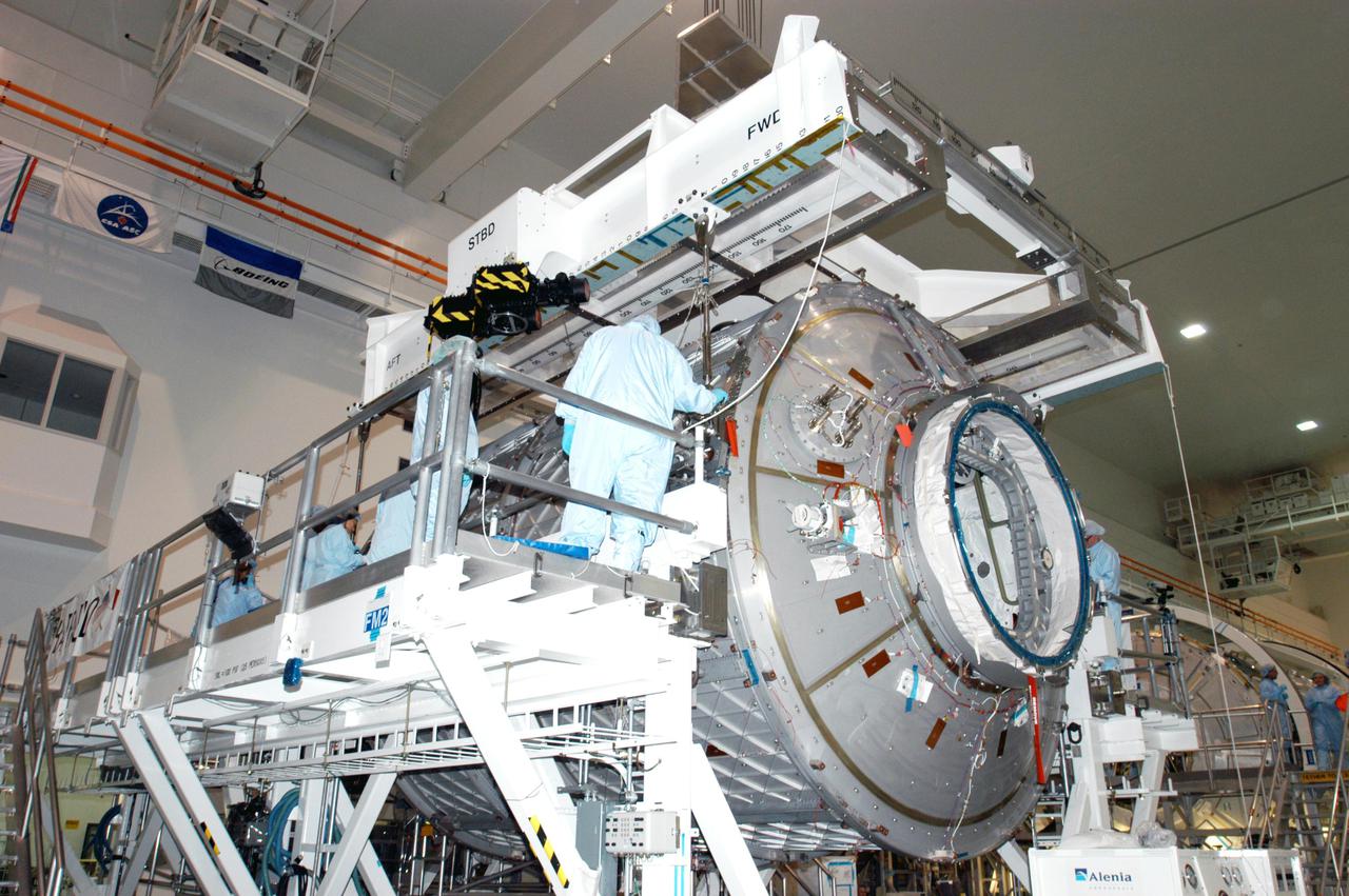 KENNEDY SPACE CENTER, FLA. -  In the Space Station Processing Facility, workers stand by as the Multi-Purpose Logistics Module Leonardo settles onto the Cargo Element Work Stand that Raffaello recently vacated.  The payload canister was a temporary location during the switch.  Three MPLMs were built by the Italian Space Agency - Donatello, Leonardo and Raffaello - to serve as a reusable logistics carrier and primary delivery system to resupply and return cargo requiring a pressurized environment to the International Space Station.