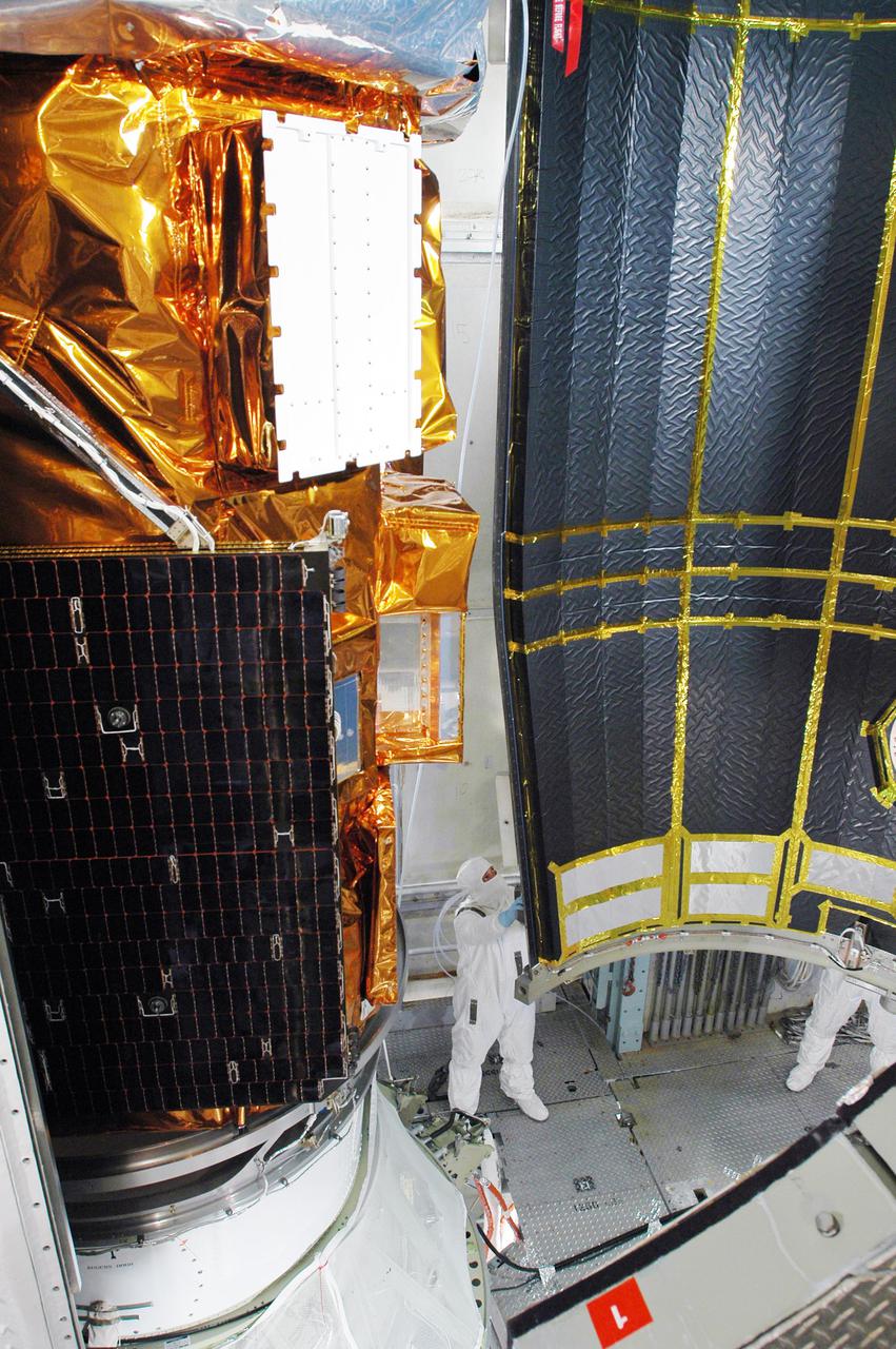 KENNEDY SPACE CENTER, FLA. - Boeing workers help guide a section of the fairing into place around the Swift spacecraft inside the mobile service tower on Launch Pad 17-A, Cape Canaveral Air Force Station. The fairing is being installed around the payload for protection during launch and ascent. A Boeing Delta II rocket is the launch vehicle for the Swift spacecraft and its Gamma-Ray Burst Mission. Swift is a first-of-its-kind multi-wavelength observatory dedicated to the study of gamma-ray burst science. Its three instruments will work together to observe GRBs and afterglows in the gamma ray, X-ray, ultraviolet and optical wavebands. Swift is scheduled to launch Nov. 17 at 12:09 p.m. EST.