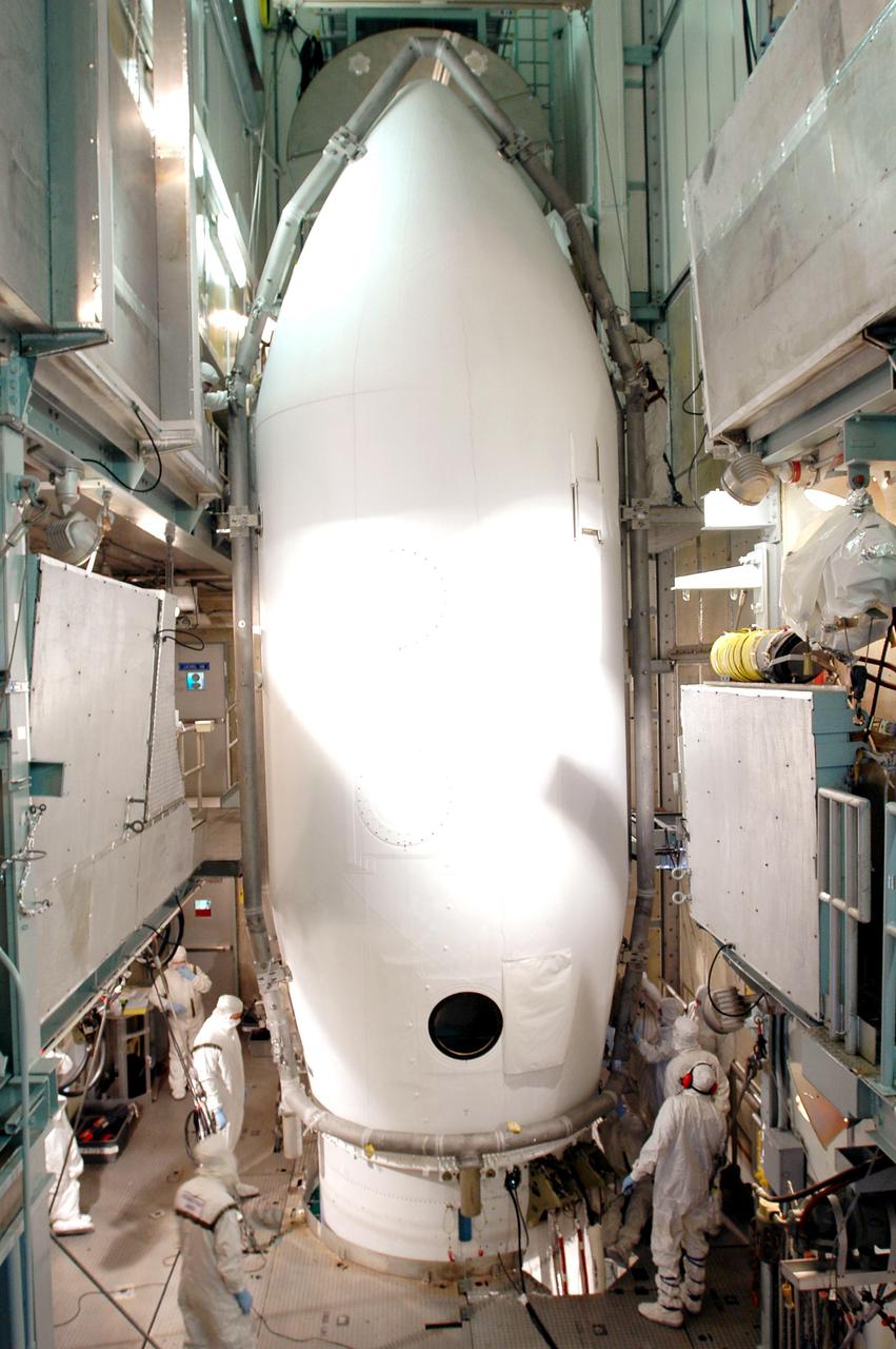 KENNEDY SPACE CENTER, FLA. - Inside the mobile service tower on Launch Pad 17-A, Cape Canaveral Air Force Station, workers begin attaching the two segments of the fairing around the Swift spacecraft. The fairing is being installed around the payload for protection during launch and ascent. A Boeing Delta II rocket is the launch vehicle for the Swift spacecraft and its Gamma-Ray Burst Mission. Swift is a first-of-its-kind multi-wavelength observatory dedicated to the study of gamma-ray burst science. Its three instruments will work together to observe GRBs and afterglows in the gamma ray, X-ray, ultraviolet and optical wavebands. Swift is scheduled to launch Nov. 17 at 12:09 p.m. EST.