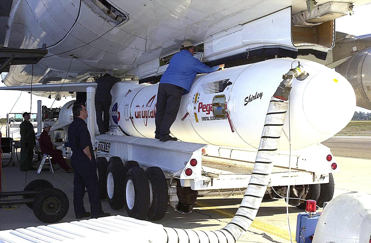 KENNEDY SPACE CENTER, FLA. - At Vandenberg Air Force Base in California, a worker stands on the transporter to attach the Orbital Sciences Pegasus XL launch vehicle and Demonstration of Autonomous Rendezvous Technology (DART) spacecraft to the underbelly of the Orbital Sciences L-1011 aircraft for launch Nov. 9. DART was designed and built for NASA by Orbital Sciences as an advanced flight demonstrator to locate and maneuver near an orbiting satellite. The DART spacecraft weighs about 800 pounds and is nearly 6 feet long and 3 feet in diameter. The Pegasus XL vehicle will launch DART into a circular polar orbit of approximately 475 miles. Once in orbit, DART will make contact with a target satellite, the Multiple Paths, Beyond-Line-of-Sight Communications (MUBLCOM), also built by Orbital Sciences and launched in 1999. DART will then perform several close-proximity operations, such as moving toward and away from the satellite using navigation data provided by on-board sensors. The entire mission will last only 24 hours and will be accomplished without human intervention. The DART flight computer will determine its own path to accomplish its mission objectives.