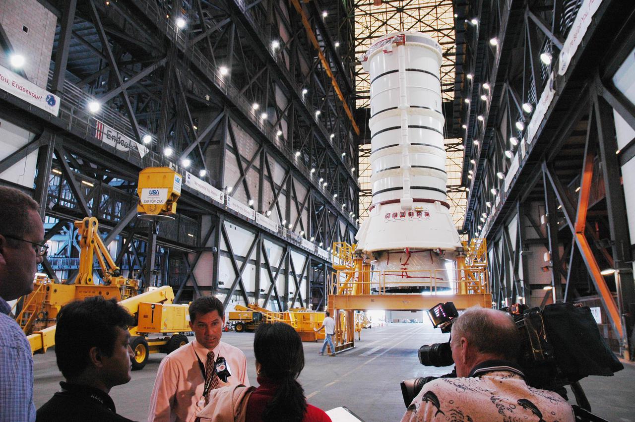 KENNEDY SPACE CENTER, FLA. -   Inside the Vehicle Assembly Building, NASA ET_SRB Operations Manager Ken Tenbusch provides information for the media about the stacking of the aft skirt and lower segment of the Solid Rocket Booster in the background.  These first segments are a significant milestone in the preparations for Return to Flight mission STS-114.  Two SRBs support the liftoff of the Space Shuttle on a launch.  The twin 149-foot tall, 12-foot diameter SRBs provide the main propulsion system during launch to place the 180,000-pound orbiters in the proper orbit around the Earth.  They operate parallel with the Space Shuttle main engines for the first two minutes of flight and jettison away from the orbiter with help from the Booster Separation Motors, about 26.3 nautical miles above the Earth’s surface.