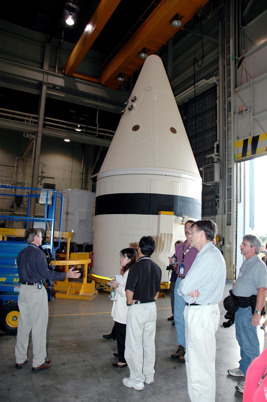 KENNEDY SPACE CENTER, FLA. -   The media tour the Solid Rocket Booster (SRB) Assembly and Refurbishment Facility where SRB segments are refurbished.  In the background can be seen the frustum and nose cap of an SRB.  The media event featured the movement of the first SRB segments to the Vehicle Assembly Building for stacking for Return to Flight mission STS-114. Two SRBs support the liftoff of the Space Shuttle on a launch.  The twin 149-foot tall, 12-foot diameter SRBs provide the main propulsion system during launch to place the orbiters in the proper orbit around the Earth.  They operate parallel with the Space Shuttle main engines for the first two minutes of flight and jettison away from the orbiter, with help from the Booster Separation Motors, about 26.3 nautical miles above the Earth’s surface.