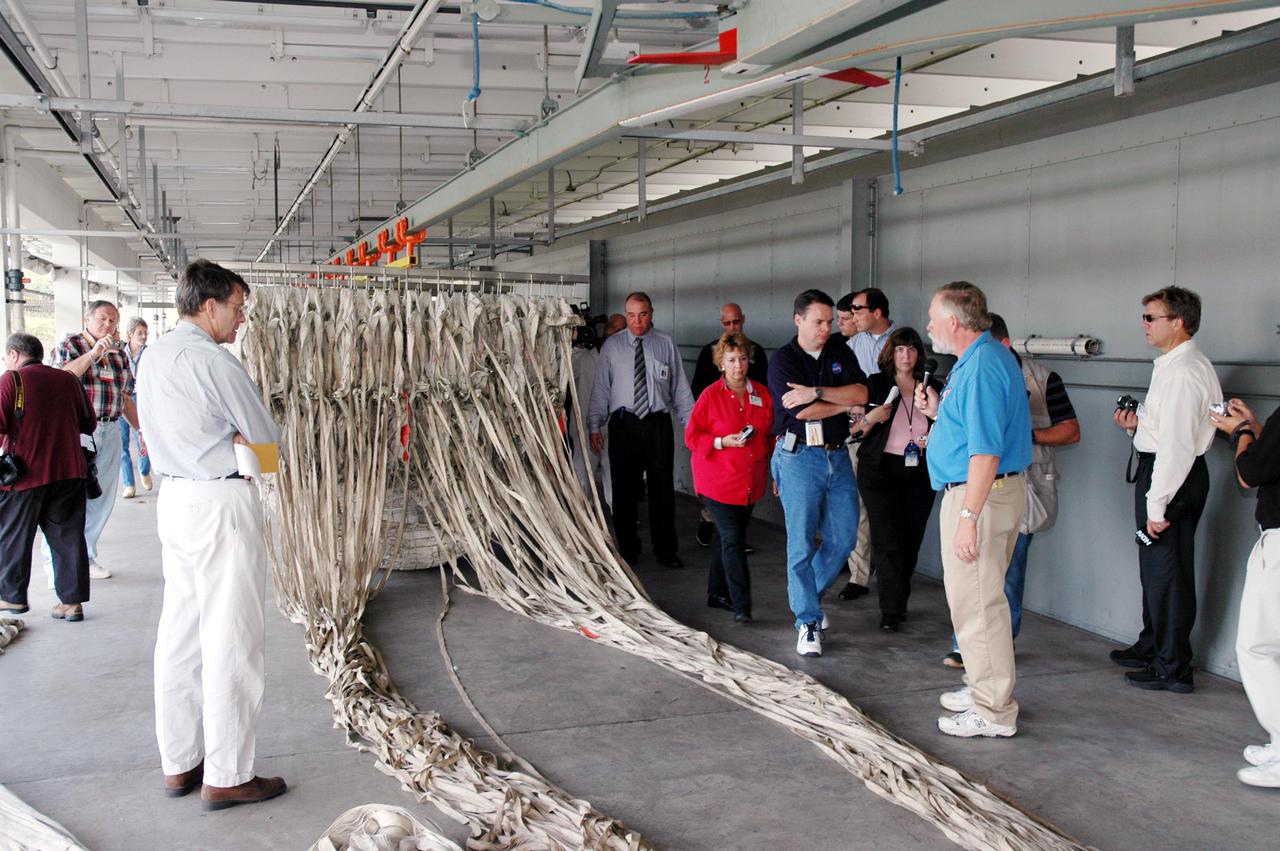 KENNEDY SPACE CENTER, FLA. -  The media tour the Parachute Refurbishment Facility, which cleans and repairs the Solid Rocket Booster (SRB) parachutes after a Space Shuttle launch.   The stop was part of a day-long event that featured the movement of the first SRB segments to the Vehicle Assembly Building for stacking for Return to Flight mission STS-114. Two SRBs support the liftoff of the Space Shuttle on a launch.  The twin 149-foot tall, 12-foot diameter SRBs provide the main propulsion system during launch to place the orbiters in the proper orbit around the Earth.  They operate parallel with the Space Shuttle main engines for the first two minutes of flight and jettison away from the orbiter, with help from the Booster Separation Motors, about 26.3 nautical miles above the Earth’s surface.