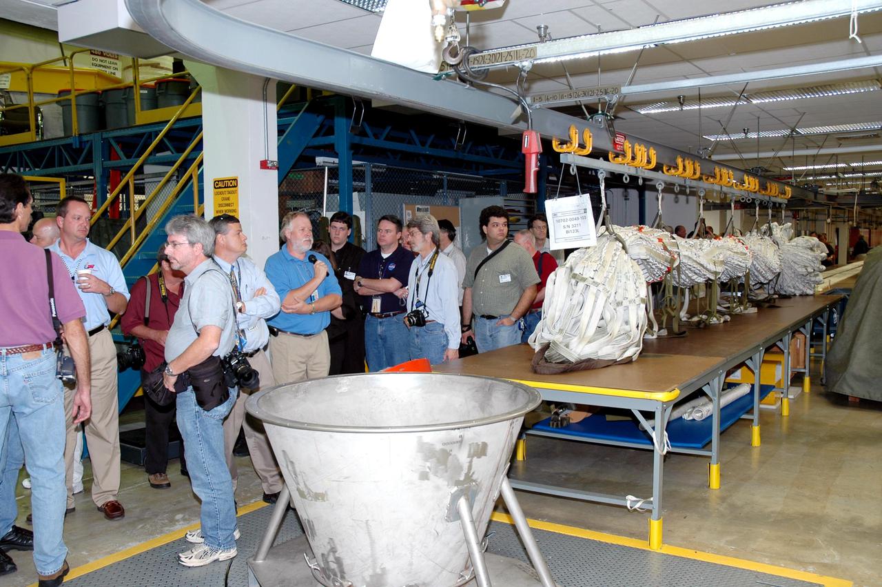 KENNEDY SPACE CENTER, FLA. -  The media tour the Parachute Refurbishment Facility, which cleans and repairs the Solid Rocket Booster (SRB) parachutes after a Space Shuttle launch.   The stop was part of a day-long event that featured the movement of the first SRB segments to the Vehicle Assembly Building for stacking for Return to Flight mission STS-114. Two SRBs support the liftoff of the Space Shuttle on a launch.  The twin 149-foot tall, 12-foot diameter SRBs provide the main propulsion system during launch to place the orbiters in the proper orbit around the Earth.  They operate parallel with the Space Shuttle main engines for the first two minutes of flight and jettison away from the orbiter, with help from the Booster Separation Motors, about 26.3 nautical miles above the Earth’s surface.