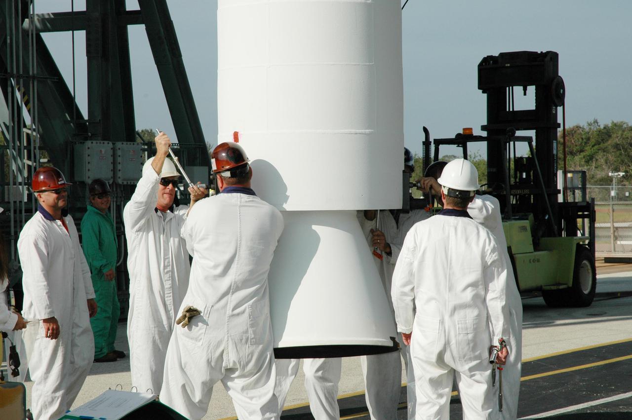 KENNEDY SPACE CENTER, FLA. - On Launch Pad 17-B, Cape Canaveral Air Force Station, Fla., workers prepare another Solid Rocket Booster (SRB) to be lifted up the mobile service tower and attached to the Boeing Delta II launch vehicle for launch of the Deep Impact spacecraft. A NASA Discovery mission, Deep Impact will probe beneath the surface of Comet Tempel 1 on July 4, 2005, when the comet is 83 million miles from Earth, and reveal the secrets of its interior. After releasing a 3- by 3-foot projectile to crash onto the surface, Deep Impact’s flyby spacecraft will collect pictures and data of how the crater forms, measuring the crater’s depth and diameter, as well as the composition of the interior of the crater and any material thrown out, and determining the changes in natural outgassing produced by the impact. It will send the data back to Earth through the antennas of the Deep Space Network. Deep Impact project management is handled by the Jet Propulsion Laboratory in Pasadena, Calif. The spacecraft is scheduled to launch Dec. 30, 2004.