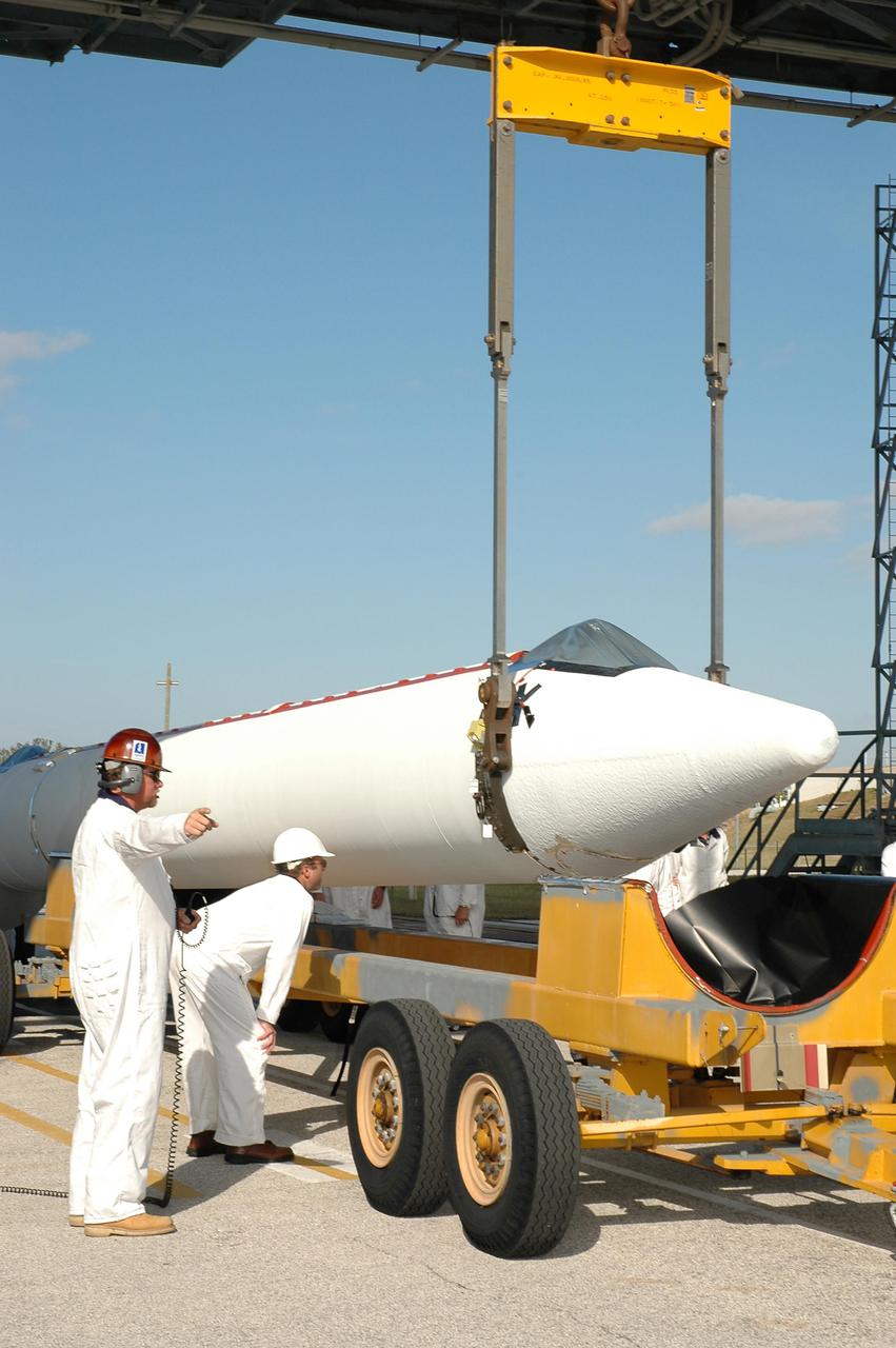 KENNEDY SPACE CENTER, FLA. -  On Launch Pad 17-B, Cape Canaveral Air Force Station, Fla., a crane begins lifting the third in a set of three Solid Rocket Boosters (SRBs).  The SRBs will be hoisted up the mobile service tower and join three others already mated to the Boeing Delta II rocket that will launch the Deep Impact spacecraft. A NASA Discovery mission, Deep Impact will probe beneath the surface of Comet Tempel 1 on July 4, 2005, when the comet is 83 million miles from Earth, and reveal the secrets of its interior.  After releasing an impactor on a course to hit the comet’s sunlit side, Deep Impact’s flyby spacecraft will collect pictures and data of how the crater forms, measure the crater’s depth and diameter, as well as the composition of the interior of the crater and any material thrown out, and determine the changes in natural outgassing produced by the impact.  It will send the data back to Earth through the antennas of the Deep Space Network.