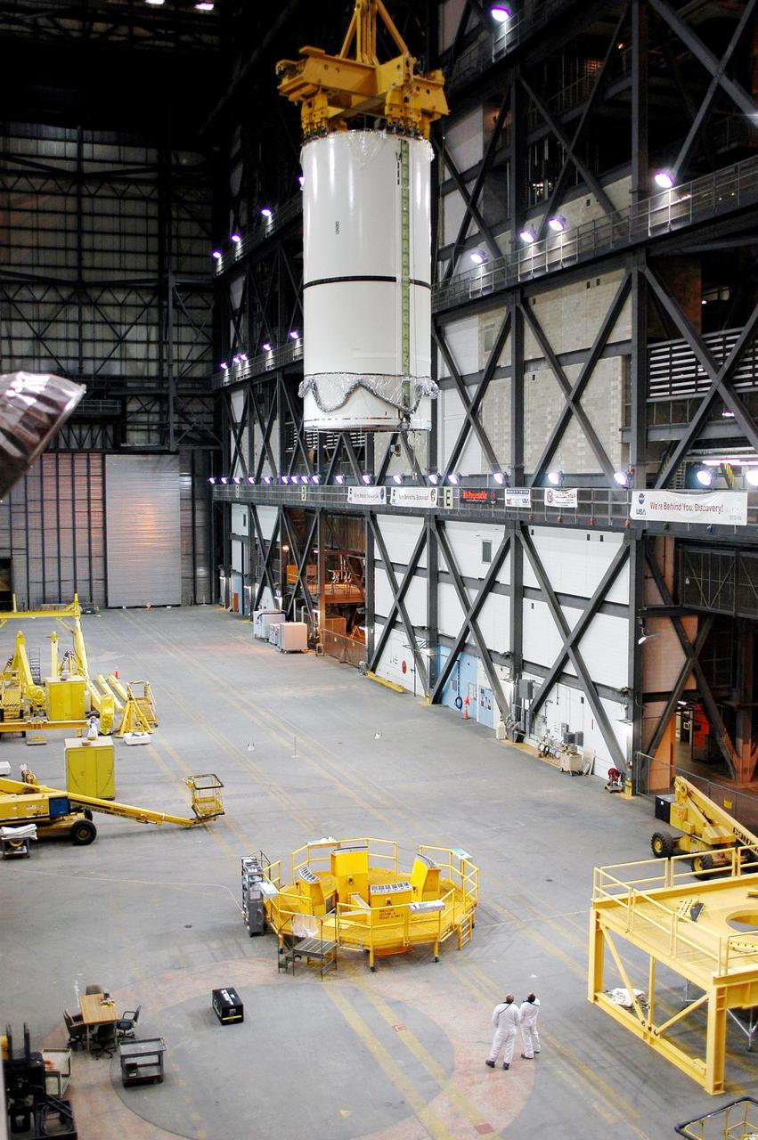 KENNEDY SPACE CENTER, FLA. -  In the transfer aisle of the Vehicle Assembly Building (VAB), a segment of a Solid Rocket Booster (SRB) is lifted from a transporter toward the 16th level.  This right aft center segment will be stacked with the aft booster that arrived in the VAB Nov. 22 for the Return to Flight mission STS-114.  Two SRBs are stacked on the Mobile Launch Platform and later joined by the External Tank.. The twin 149-foot tall, 12-foot diameter SRBs provide the main propulsion system during launch. They operate parallel with the Space Shuttle main engines for the first two minutes of flight and jettison away from the orbiter with help from the Booster Separation Motors, about 26.3 nautical miles above the Earth’s surface.
