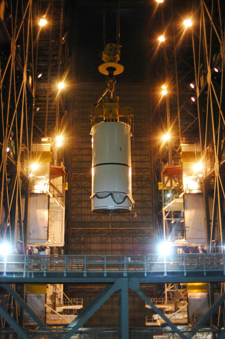 KENNEDY SPACE CENTER, FLA. -  In the Vehicle Assembly Building (VAB), a segment of a Solid Rocket Booster (SRB) is  lifted over the cross walk at the 16th level.  This right aft center segment will be stacked with the aft booster on the other side that arrived in the VAB Nov. 22 for the Return to Flight mission STS-114.  Two SRBs are stacked on the Mobile Launch Platform and later joined by the External Tank.. The twin 149-foot tall, 12-foot diameter SRBs provide the main propulsion system during launch. They operate parallel with the Space Shuttle main engines for the first two minutes of flight and jettison away from the orbiter with help from the Booster Separation Motors, about 26.3 nautical miles above the Earth’s surface.
