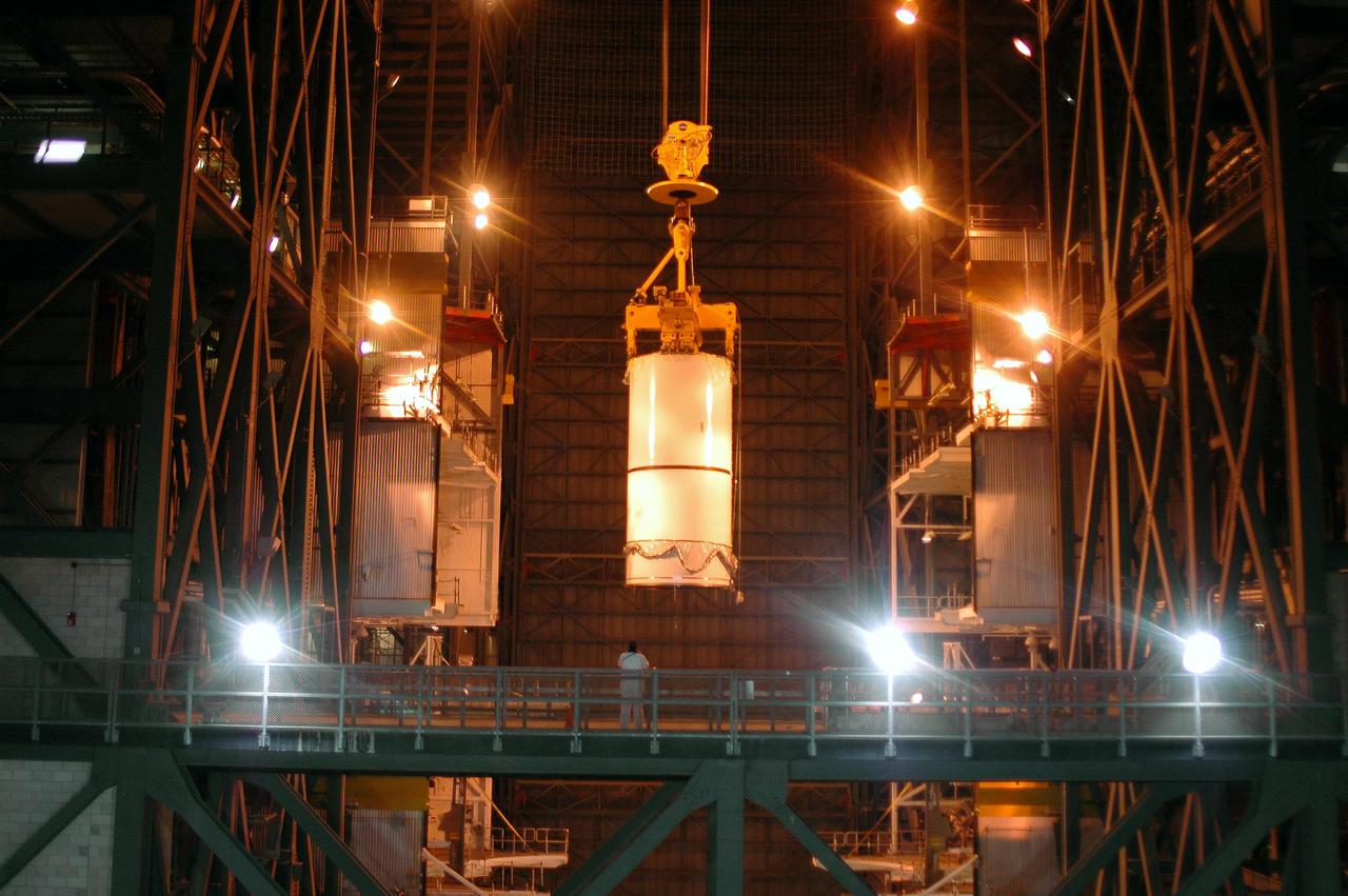 KENNEDY SPACE CENTER, FLA. -  In the Vehicle Assembly Building (VAB), a segment of a Solid Rocket Booster (SRB) is lifted over the cross walk at the 16th level.  This right aft center segment will be stacked with the aft booster on the other side that arrived in the VAB Nov. 22 for the Return to Flight mission STS-114. Two SRBs are stacked on the Mobile Launch Platform and later joined by the External Tank.. The twin 149-foot tall, 12-foot diameter SRBs provide the main propulsion system during launch. They operate parallel with the Space Shuttle main engines for the first two minutes of flight and jettison away from the orbiter with help from the Booster Separation Motors, about 26.3 nautical miles above the Earth’s surface.