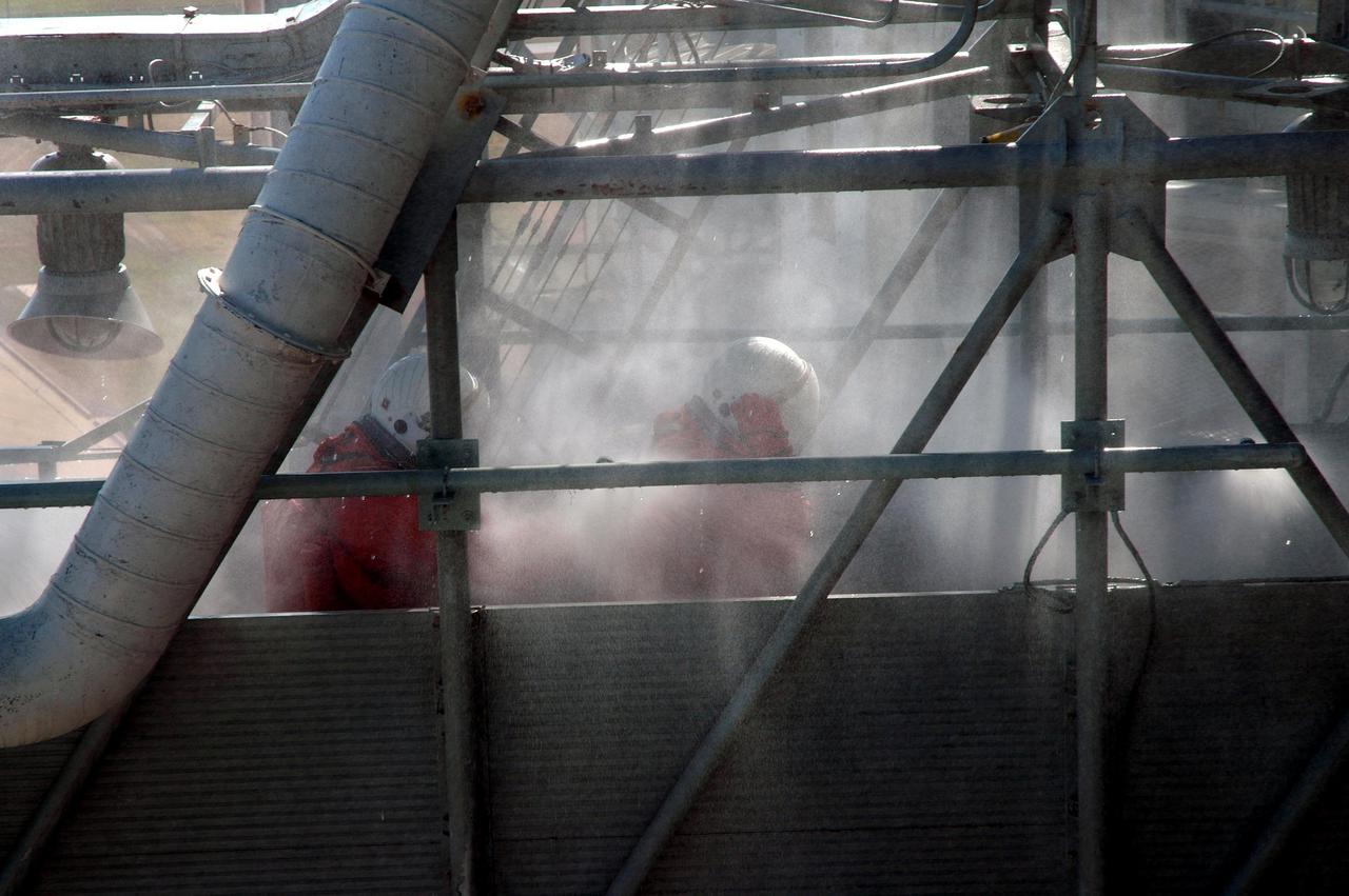 KENNEDY SPACE CENTER, FLA. -  On Launch Pad 39A, astronaut-suited workers take part in an emergency egress scenario. The four-hour exercise simulated normal launch countdown operations, with the added challenge of a fictitious event causing an evacuation of the vehicle and launch pad.  It tested the team’s rescue approaches on the Fixed Service Structure, slidewire basket evacuation, triage care and transportation of injured personnel to hospitals, as well as communications and coordination.