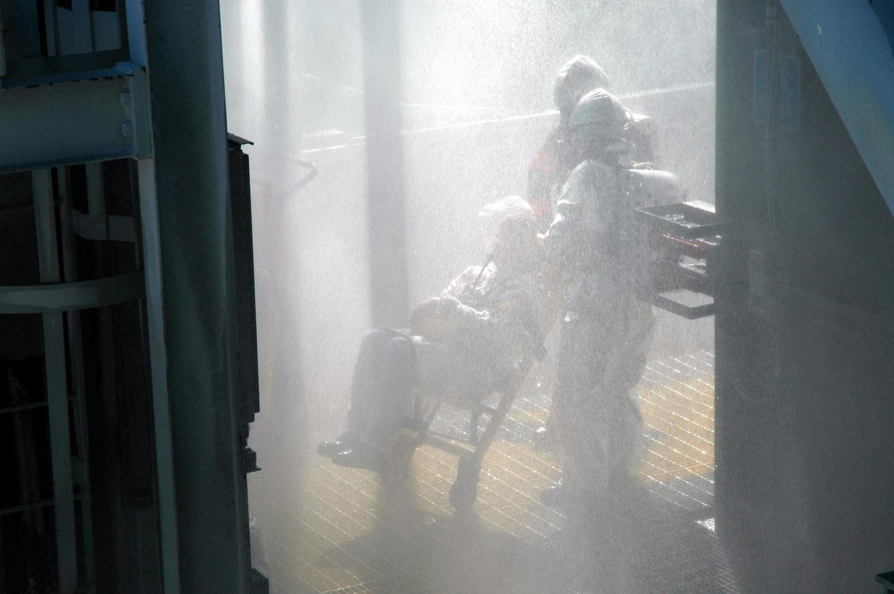 KENNEDY SPACE CENTER, FLA. -  On Launch Pad 39A, astronaut-suited workers take part in an emergency egress scenario. The four-hour exercise simulated normal launch countdown operations, with the added challenge of a fictitious event causing an evacuation of the vehicle and launch pad.  It tested the team’s rescue approaches on the Fixed Service Structure, slidewire basket evacuation, triage care and transportation of injured personnel to hospitals, as well as communications and coordination.