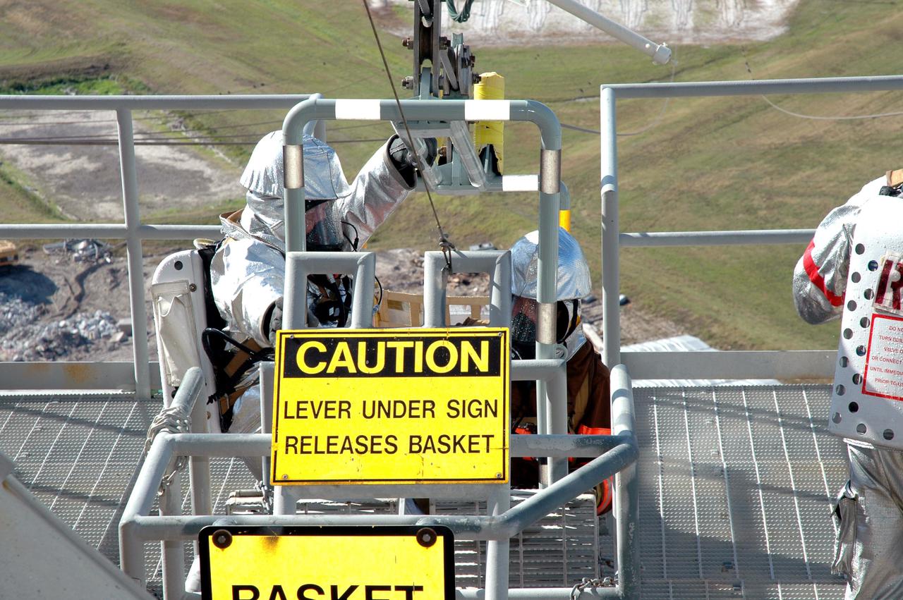 KENNEDY SPACE CENTER, FLA. -  On Launch Pad 39A, a rescue force climbs into slidewire baskets on the Fixed Service Structure during an emergency egress scenario.  The four-hour exercise simulated normal launch countdown operations, with the added challenge of a fictitious event causing an evacuation of the vehicle and launch pad.  It tested the team’s rescue approaches on the Fixed Service Structure, slidewire basket evacuation, triage care and transportation of injured personnel to hospitals, as well as communications and coordination.