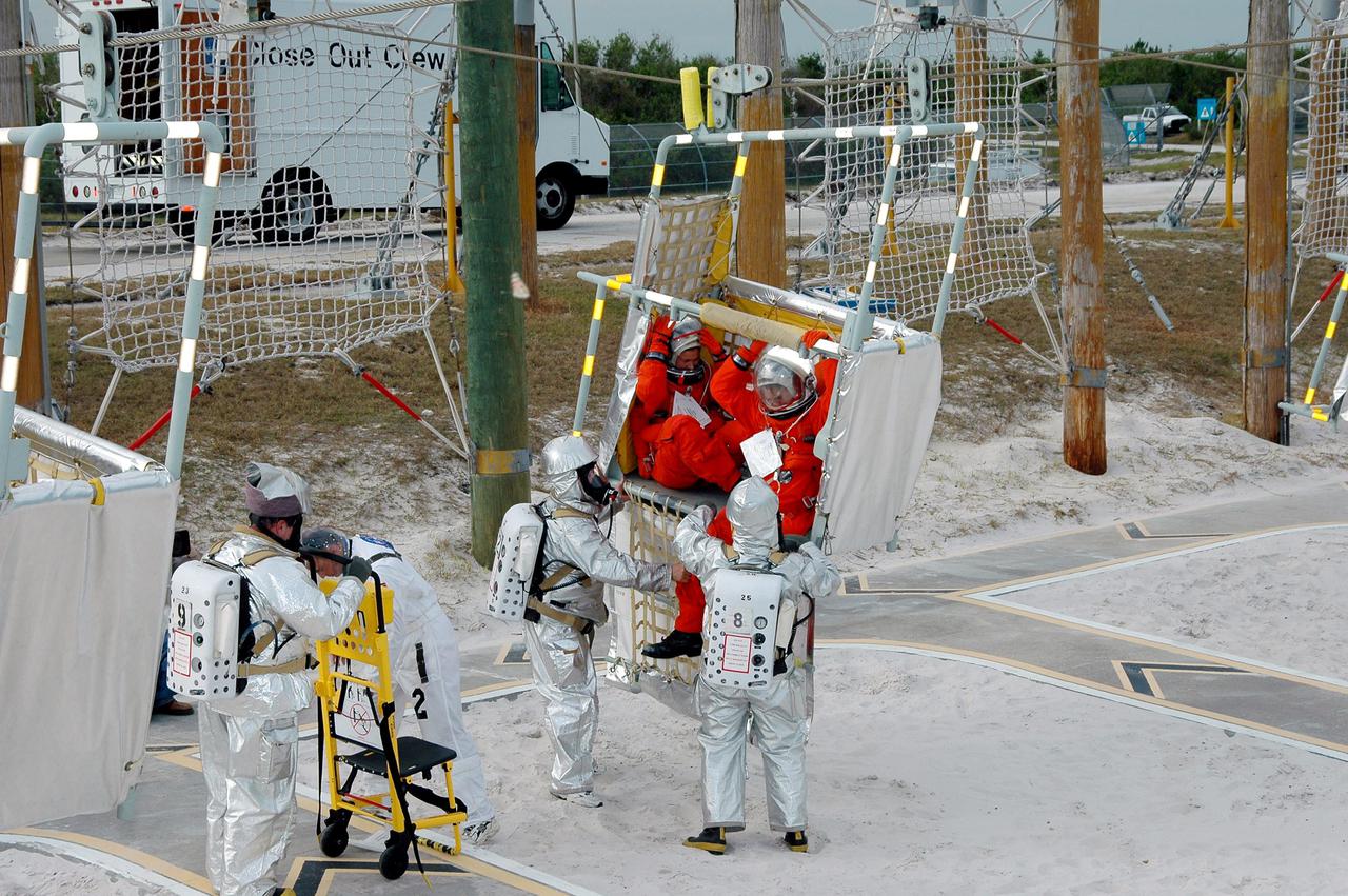 KENNEDY SPACE CENTER, FLA. -  On Launch Pad 39A, rescue team members and astronaut-suited workers exit a slidewire basket during an emergency egress scenario.  The four-hour exercise simulated normal launch countdown operations, with the added challenge of a fictitious event causing an evacuation of the vehicle and launch pad.  It tested the team’s rescue approaches on the Fixed Service Structure, slidewire basket evacuation, triage care and transportation of injured personnel to hospitals, as well as communications and coordination.