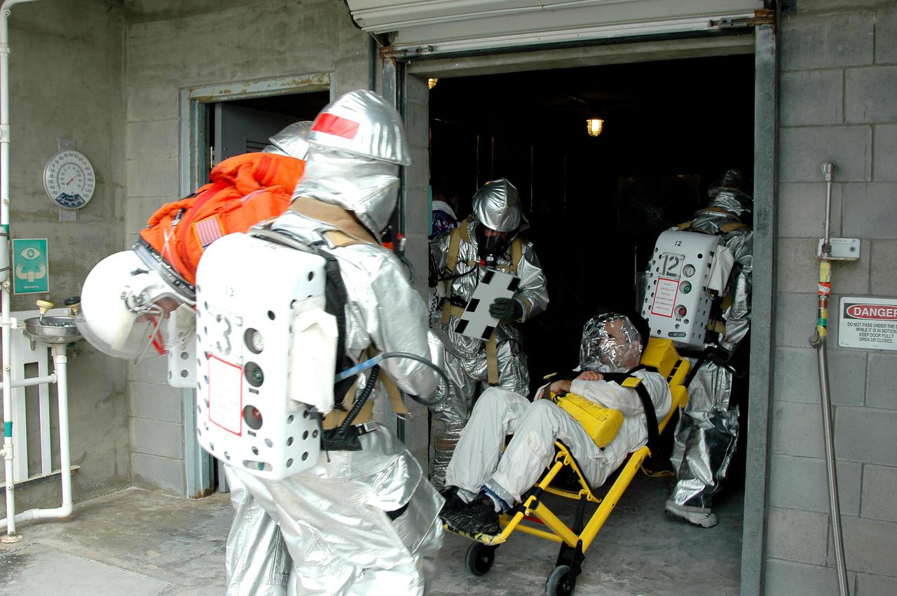 KENNEDY SPACE CENTER, FLA. -  During a simulated launch countdown_emergency simulation on Launch Pad 39A, the rescue team takes “injured” astronaut-suited workers into the pad bunker.  The four-hour exercise simulated normal launch countdown operations, with the added challenge of a fictitious event causing an evacuation of the vehicle and launch pad.  It tested the team’s rescue approaches on the Fixed Service Structure, slidewire basket evacuation, triage care and transportation of injured personnel to hospitals, as well as communications and coordination.