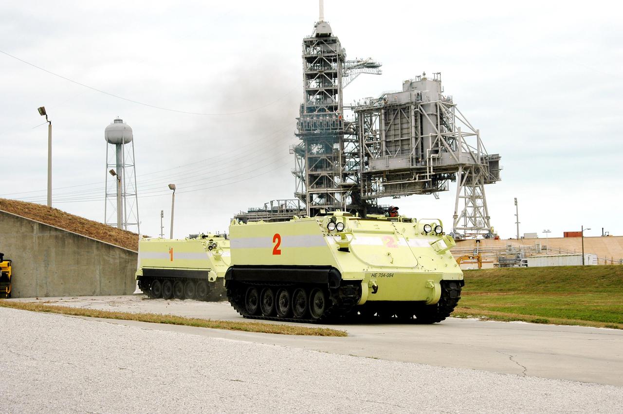 KENNEDY SPACE CENTER, FLA. - During a simulated launch countdown_emergency simulation on Launch Pad 39A, M-113 armored personnel carriers transport workers away from the pad. In the background are the Fixed (tall) and Rotating Service Structures. To the left is the water tower that holds 300,000 gallons used during liftoffs.The four-hour exercise simulated normal launch countdown operations, with the added challenge of a fictitious event causing an evacuation of the vehicle and launch pad. It tested the team’s rescue approaches on the Fixed Service Structure, slidewire basket evacuation, triage care and transportation of injured personnel to hospitals, as well as communications and coordination.