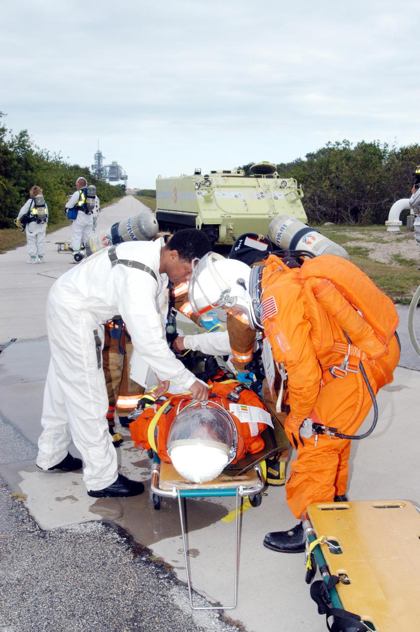 KENNEDY SPACE CENTER, FLA. -  During a simulated launch countdown_emergency simulation on Launch Pad 39A, the rescue team moves “injured” astronaut-suited workers out of the M-113 armored personnel carriers that transported them away from the pad (seen in the distance).  Pad team members participated in the four-hour exercise simulating normal launch countdown operations, with the added challenge of a fictitious event causing an evacuation of the vehicle and launch pad.  The simulation tested the team’s rescue approaches on the Fixed Service Structure, slidewire basket evacuation, triage care and transportation of injured personnel to hospitals, as well as communications and coordination.