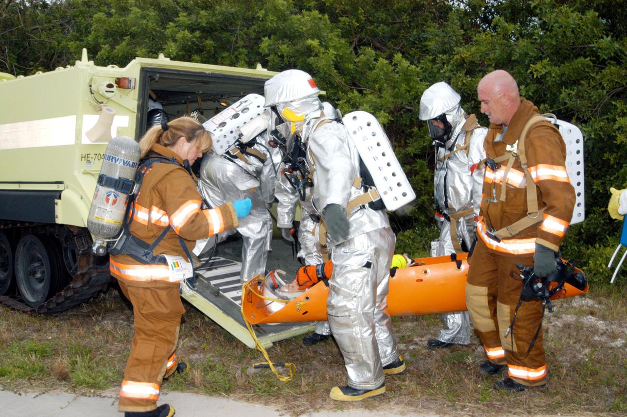 KENNEDY SPACE CENTER, FLA. -  During a simulated launch countdown_emergency simulation on Launch Pad 39A, the rescue team moves “injured” astronaut-suited workers out of the M-113 armored personnel carriers that transported them away from the pad (seen in the distance).  Pad team members participated in the four-hour exercise simulating normal launch countdown operations, with the added challenge of a fictitious event causing an evacuation of the vehicle and launch pad.  The simulation tested the team’s rescue approaches on the Fixed Service Structure, slidewire basket evacuation, triage care and transportation of injured personnel to hospitals, as well as communications and coordination.