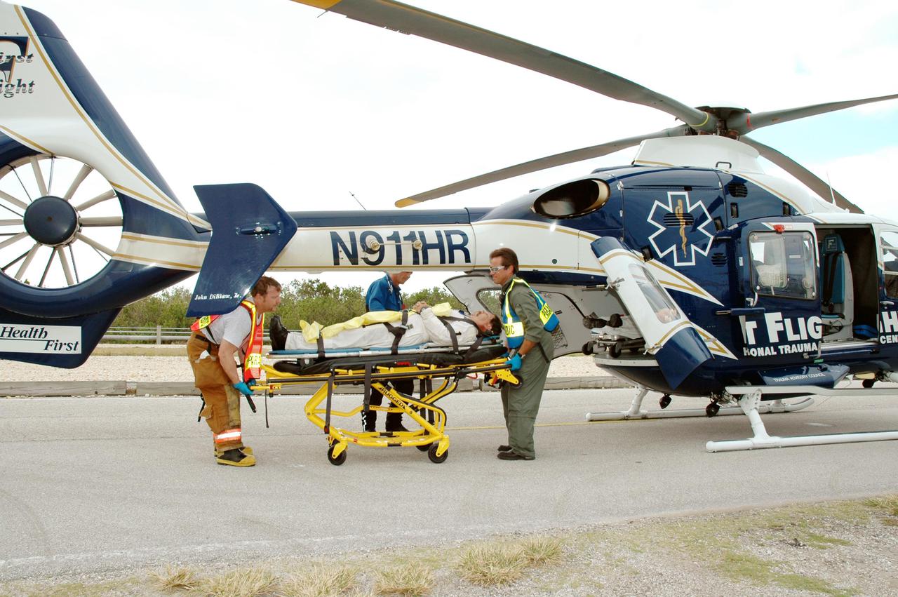 KENNEDY SPACE CENTER, FLA. -  During a simulated launch countdown_emergency simulation on Launch Pad 39A, astronaut-suited workers are placed in a medical-rescue helicopter for transport to a hospital participating in the simulation.  Pad team members took part in the four-hour exercise simulating normal launch countdown operations, with the added challenge of a fictitious event causing an evacuation of the vehicle and launch pad.  The simulation tested the team’s rescue approaches on the Fixed Service Structure, slidewire basket evacuation, triage care and transportation of injured personnel to hospitals, as well as communications and coordination.