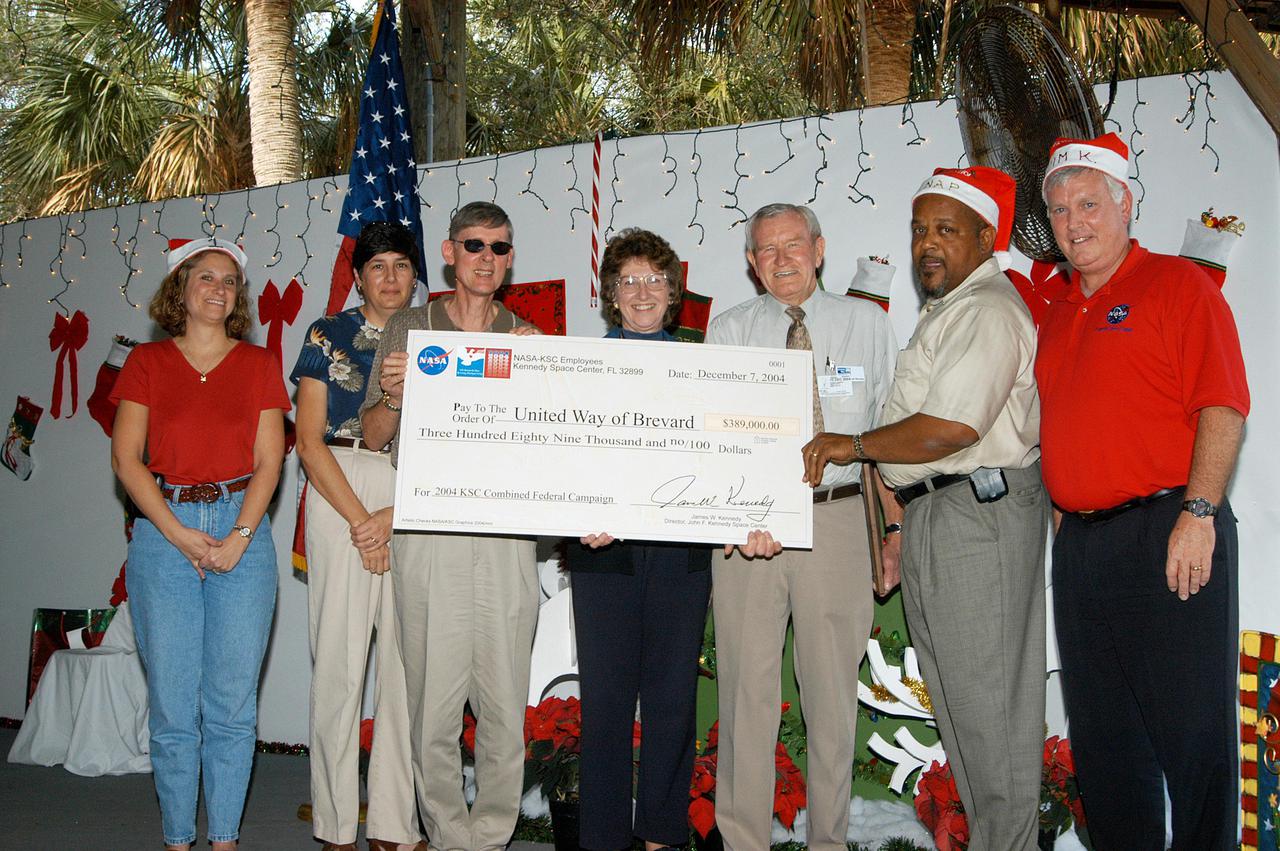 KENNEDY SPACE CENTER, FLA. -  The KSC Holiday Celebration was also the occasion for presenting the Center’s Combined Federal Campaign check to United Way of Brevard.  The 2004 campaign netted $389,000 in donations.  At right is Center Director Jim Kennedy.  Next to him, at left, is the campaign chairman, KSC’s Chief Financial Officer, Nap Carroll.