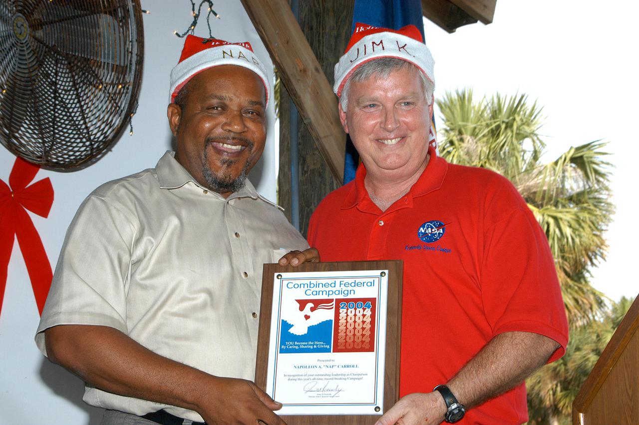 KENNEDY SPACE CENTER, FLA. -  Center Director Jim Kennedy (right) presents a plaque to the Center’s Chief Financial Officer, Nap Carroll, who spearheaded the Kennedy Space Center Combined Federal Campaign.  The 2004 campaign netted $389,000 to donate to the United Way of Brevard.
