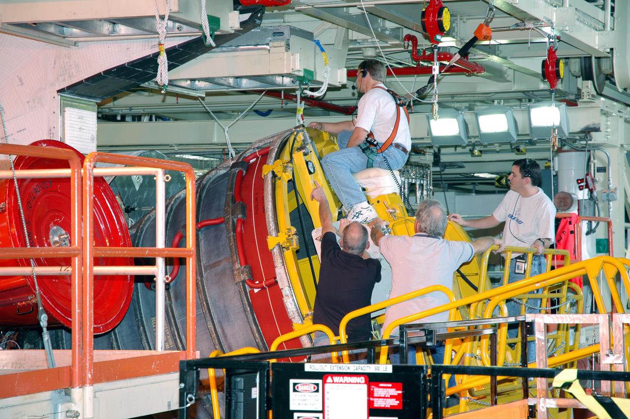 KENNEDY SPACE CENTER, FLA. -  In the Orbiter Processing Facility, a technician appears to ride the Space Shuttle Main Engine (SSME) as he maneuvers the SSME on the Hyster lift into position for installation on Discovery, the vehicle designated for the Return to Flight mission STS-114. Overall, an SSME weighs approximately 7,000 pounds. An SSME operates at greater temperature extremes than any mechanical system in common use today. The liquid hydrogen fuel is -423 degrees Fahrenheit, the second coldest liquid on Earth. When the hydrogen is burned with liquid oxygen, the temperature in the engine's combustion chamber reaches +6000 degrees Fahrenheit -- that's higher than the boiling point of Iron.  The maximum equivalent horsepower developed by the three SSMEs is just over 37 million horsepower.  The energy released by the three SSMEs is equivalent to the output of 23 Hoover Dams.
