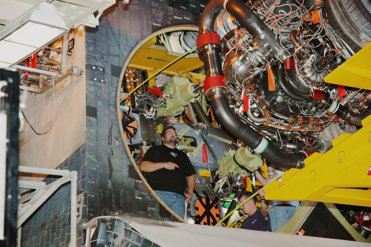 KENNEDY SPACE CENTER, FLA. - In the Orbiter Processing Facility, a technician watches closely as the third Space Shuttle Main Engine (SSME) is moved into position behind Discovery for installation. Discovery is designated as the Return to Flight vehicle for mission STS-114. Recent improvements to the SSME include the introduction of redesigned high-pressure turbopumps into the SSME fleet. The new pumps are designed and built by Pratt and Whitney at West Palm Beach, Fla. SSMEs and the Pratt and Whitney turbopumps are tested at Stennis Space Center in Mississippi. Engines and engine components are delivered to Kennedy Space Center to be prepared for flight.