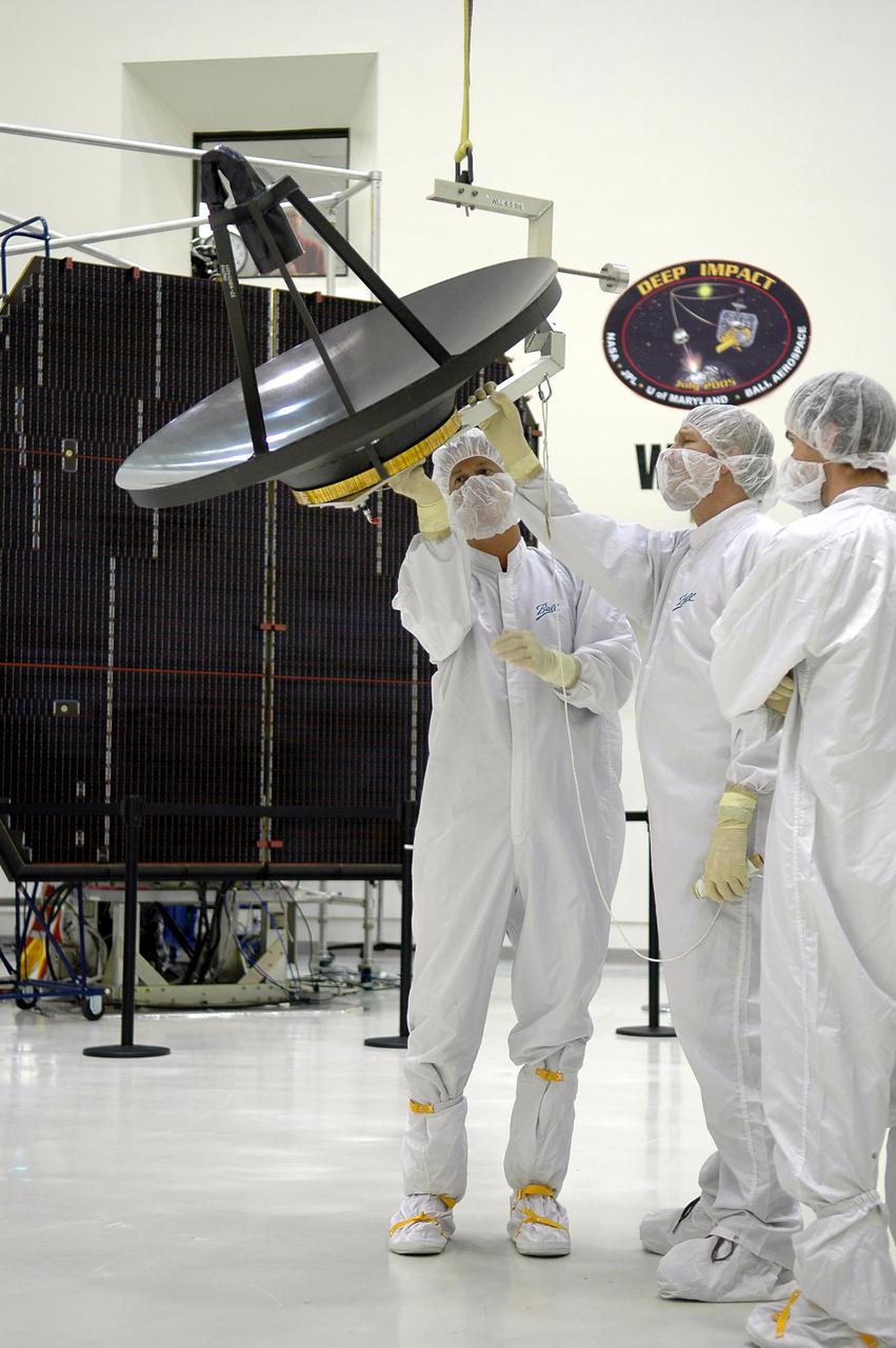 KENNEDY SPACE CENTER, FLA. -  Ball Aerospace technicians at Astrotech in Titusville, Fla., make sure the crane is securely attached to the high-gain communications antenna to be installed on the Deep Impact spacecraft. A NASA Discovery mission, Deep Impact will probe beneath the surface of Comet Tempel 1 on July 4, 2005, when the comet is 83 million miles from Earth, and reveal the secrets of its interior.   During the encounter phase, the high-gain antenna transmits near-real-time images of the impact back to Earth. The spacecraft is scheduled to launch Jan. 8 aboard a Boeing Delta II rocket from Launch Complex 17-B at Cape Canaveral Air Force Station, Fla.