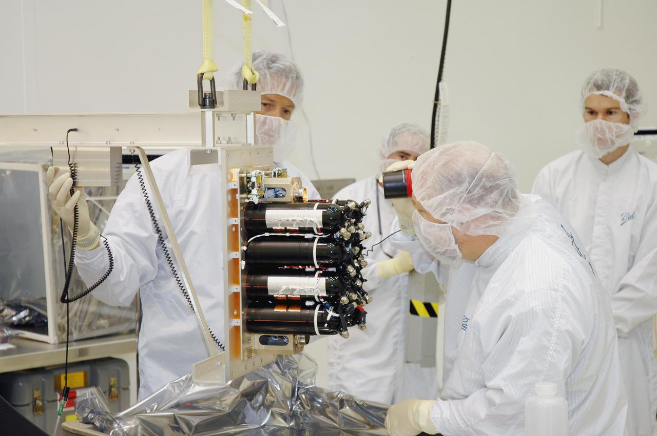KENNEDY SPACE CENTER, FLA. - Ball Aerospace technicians check the flight battery for the Deep Impact flyby spacecraft before installation at Astrotech Space Operations in Titusville, Fla. About the size of a Ford Explorer, the flyby spacecraft is three-axis stabilized and uses a fixed solar array and a small NiH2 battery for its power system. A NASA Discovery mission, Deep Impact will probe beneath the surface of Comet Tempel 1 on July 4, 2005, when the comet is 83 million miles from Earth. During the encounter phase when the comet collides with the impactor projectile propelled into its path, the spacecraft’s high-gain antenna will transmit near-real-time images of the impact back to Earth. The spacecraft is scheduled to launch Jan. 8 aboard a Boeing Delta II rocket from Launch Complex 17-B at Cape Canaveral Air Force Station, Fla.
