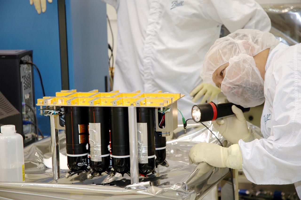 KENNEDY SPACE CENTER, FLA. - Ball Aerospace technicians at Astrotech Space Operations in Titusville, Fla., take a final look at the flight battery before moving and installing it on the Deep Impact flyby spacecraft. About the size of a Ford Explorer, the flyby spacecraft is three-axis stabilized and uses a fixed solar array and a small NiH2 battery for its power system. A NASA Discovery mission, Deep Impact will probe beneath the surface of Comet Tempel 1 on July 4, 2005, when the comet is 83 million miles from Earth. During the encounter phase when the comet collides with the impactor projectile propelled into its path, the spacecraft’s high-gain antenna will transmit near-real-time images of the impact back to Earth. The spacecraft is scheduled to launch Jan. 8 aboard a Boeing Delta II rocket from Launch Complex 17-B at Cape Canaveral Air Force Station, Fla.