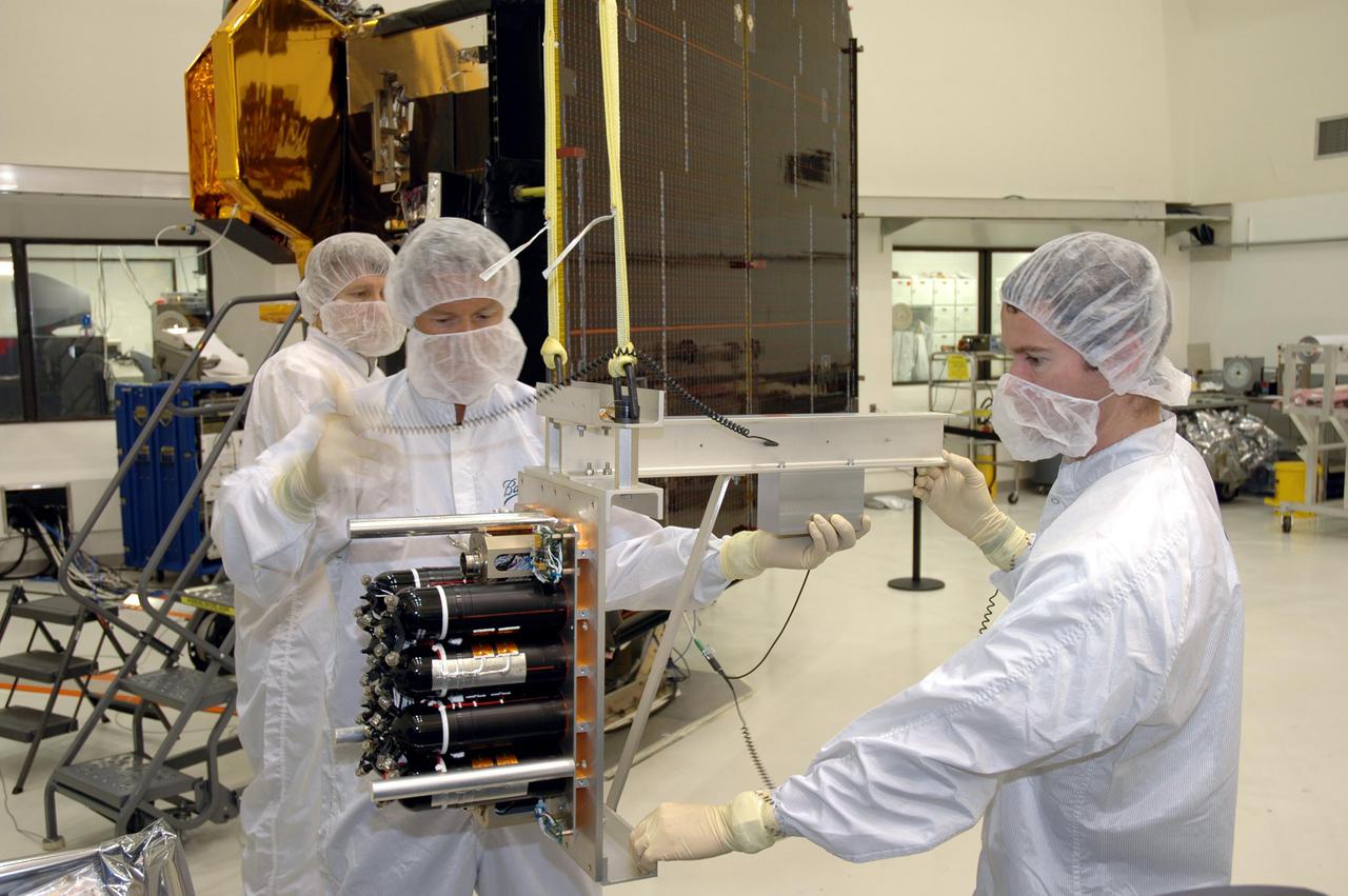 KENNEDY SPACE CENTER, FLA. - Ball Aerospace technicians at Astrotech Space Operations in Titusville, Fla., attach equipment to the flight battery to move it to the Deep Impact flyby spacecraft for installation. About the size of a Ford Explorer, the flyby spacecraft is three-axis stabilized and uses a fixed solar array and a small NiH2 battery for its power system. A NASA Discovery mission, Deep Impact will probe beneath the surface of Comet Tempel 1 on July 4, 2005, when the comet is 83 million miles from Earth. During the encounter phase when the comet collides with the impactor projectile propelled into its path, the spacecraft’s high-gain antenna will transmit near-real-time images of the impact back to Earth. The spacecraft is scheduled to launch Jan. 8 aboard a Boeing Delta II rocket from Launch Complex 17-B at Cape Canaveral Air Force Station, Fla.