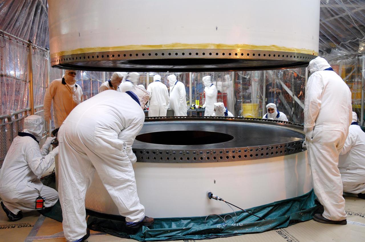 KENNEDY SPACE CENTER, FLA. - In a Vehicle Assembly Building (VAB) high bay, workers monitor the movement of a Solid Rocket Booster (SRB) aft center segment as it is lowered toward an aft segment already secured to a Mobile Launch Platform. These segments are part of the right SRB for the Space Shuttle Return to Flight mission, STS-114. Two SRBs are stacked on a Mobile Launch Platform for each Shuttle flight and later joined by an External Tank. The twin 149-foot tall, 12-foot diameter SRBs provide the main propulsion system during launch. They operate in parallel with the Space Shuttle main engines for the first two minutes of flight and jettison away from the orbiter with help from the Booster Separation Motors, about 26.3 nautical miles above the Earth’s surface.