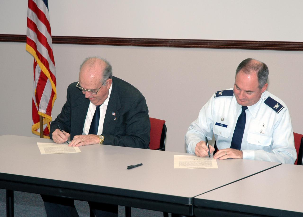 KENNEDY SPACE CENTER, FLA. -  Leaders of prominent Florida space organizations convened at the Florida Space Authority campus in Cape Canaveral to sign a memorandum of agreement with the Space Foundation to launch the first “Florida Space” conference. Dr. James W. Johnson (left), chairman of the Canaveral Council of Technical Societies, and Col. Mark H. Owen, commander of the 45th Space Wing at Patrick Air Force Base, sign copies of the agreement for their respective organizations.  Others present to sign the agreement are retired Navy Capt. Winston E. Scott, executive director of the Florida Space Authority; Dr. Woodrow Whitlow Jr., deputy director of the Kennedy Space Center; and Elliot G. Pulham, president and chief executive officer of the Space Foundation. The conference will combine and build on the best features of previous Florida space events including Space Congress and the Cape Canaveral Spaceport Symposium. Both will be retired now in favor of this new event to be held annually and operated by the Space Foundation. Florida Space 2005 will be presented in November 2005.