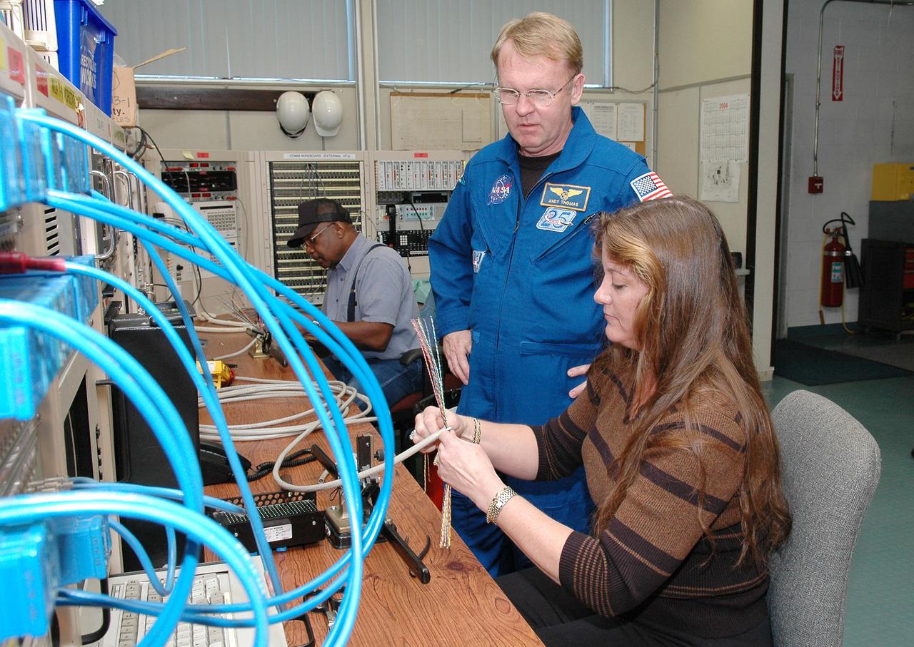 KENNEDY SPACE CENTER, FLA. -  Inside the MILA  Spaceflight Tracking and Data Network Station during a visit to Kennedy, mission STS-114 Mission Specialist Andrew Thomas watches Sonja Ashworth, with Honeywell,  as she builds communication cables.  The tracking station serves as the primary voice, data and telemetry communications link between the Shuttle and the ground from launch until 7-1_2 minutes into the flight. Millions of clues about the performance of the Space Shuttle’s main engines and other components are communicated to launch managers, technicians and engineers on the ground, who must keep their fingers on the pulse of the Space Shuttle during the critical ascent period. In a typical year, MILA provides through KSC more than 10,000 hours of data between spacecraft and data users.  MILA is also used during a Space Shuttle landing at KSC and provides communications beginning about 13 minutes before touchdown. Also, MILA can be called upon to provide data transfer support for NASA’s Expendable Launch Vehicle missions and orbiting scientific satellites.