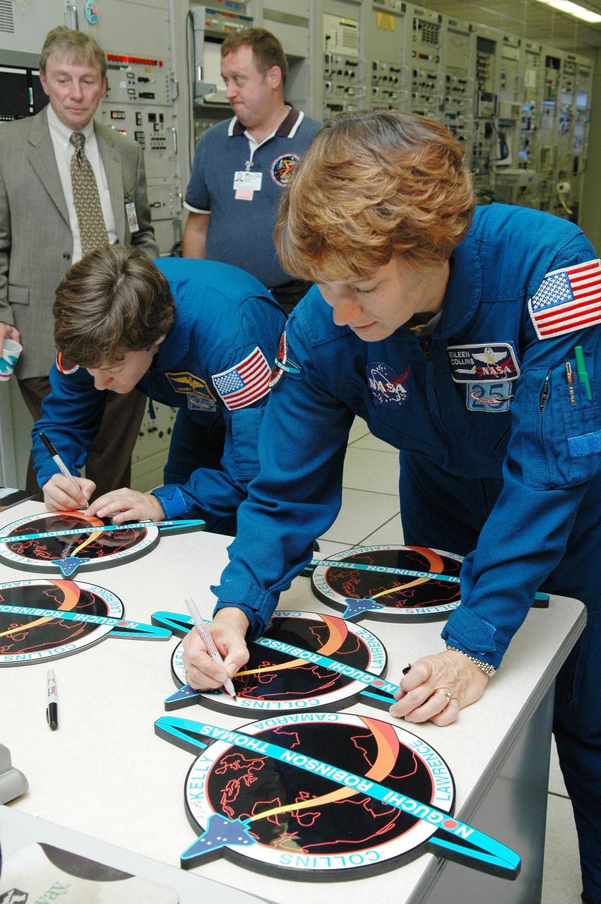 KENNEDY SPACE CENTER, FLA. -  Inside the MILA  Spaceflight Tracking and Data Network Station during a visit to Kennedy, STS-114 Mission Specialist Wendy Lawrence and Commander Eileen Collins sign crew photos and logos.  Behind Lawrence is Anthony Ippolito, current director of MILA_PDL, and William Foster, Johnson Space Center ground controller.  (MILA refers to Merritt Island Launch Area; PDL designates the Ponce De Leon Inlet site.) The tracking station serves as the primary voice, data and telemetry communications link between the Shuttle and the ground from launch until 7-1_2 minutes into the flight. Millions of clues about the performance of the Space Shuttle’s main engines and other components are communicated to launch managers, technicians and engineers on the ground, who must keep their fingers on the pulse of the Space Shuttle during the critical ascent period. In a typical year, MILA provides through KSC more than 10,000 hours of data between spacecraft and data users.  MILA is also used during a Space Shuttle landing at KSC and provides communications beginning about 13 minutes before touchdown. Also, MILA can be called upon to provide data transfer support for NASA’s Expendable Launch Vehicle missions and orbiting scientific satellites.