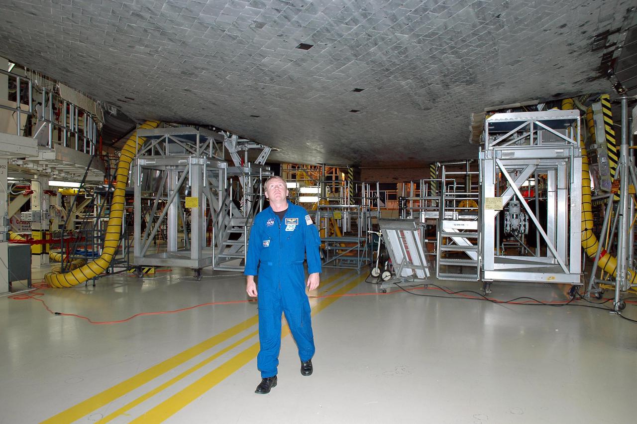 KENNEDY SPACE CENTER, FLA. -  On a visit to Kennedy, STS-114 Mission Specialist Andrew Thomas looks at the tiles, part of the Thermal Protection System, on the belly of the orbiter Discovery.  The designated vehicle for the mission, Discovery is in the Orbiter Processing Facility for launch processing. Discovery is scheduled for a launch planning window of May 12 to June 3, 2005.