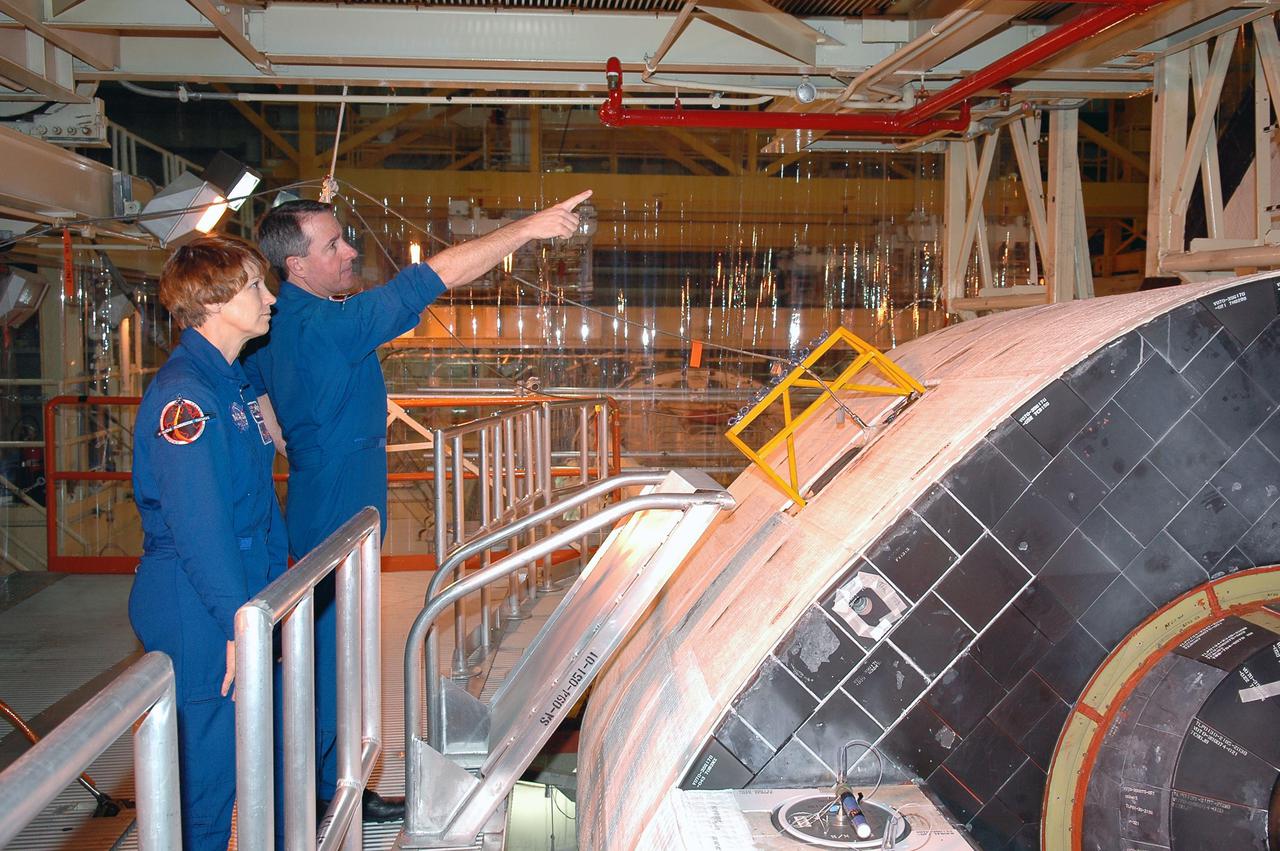 KENNEDY SPACE CENTER, FLA. -  On a visit to Kennedy, STS-114 Mission Specialist Stephen Robinson (right) points out an area above the orbiter Discovery to Commander Eileen Collins (left).  Discovery is in the Orbiter Processing Facility for launch processing. Discovery is scheduled for a launch planning window of May 12 to June 3, 2005.