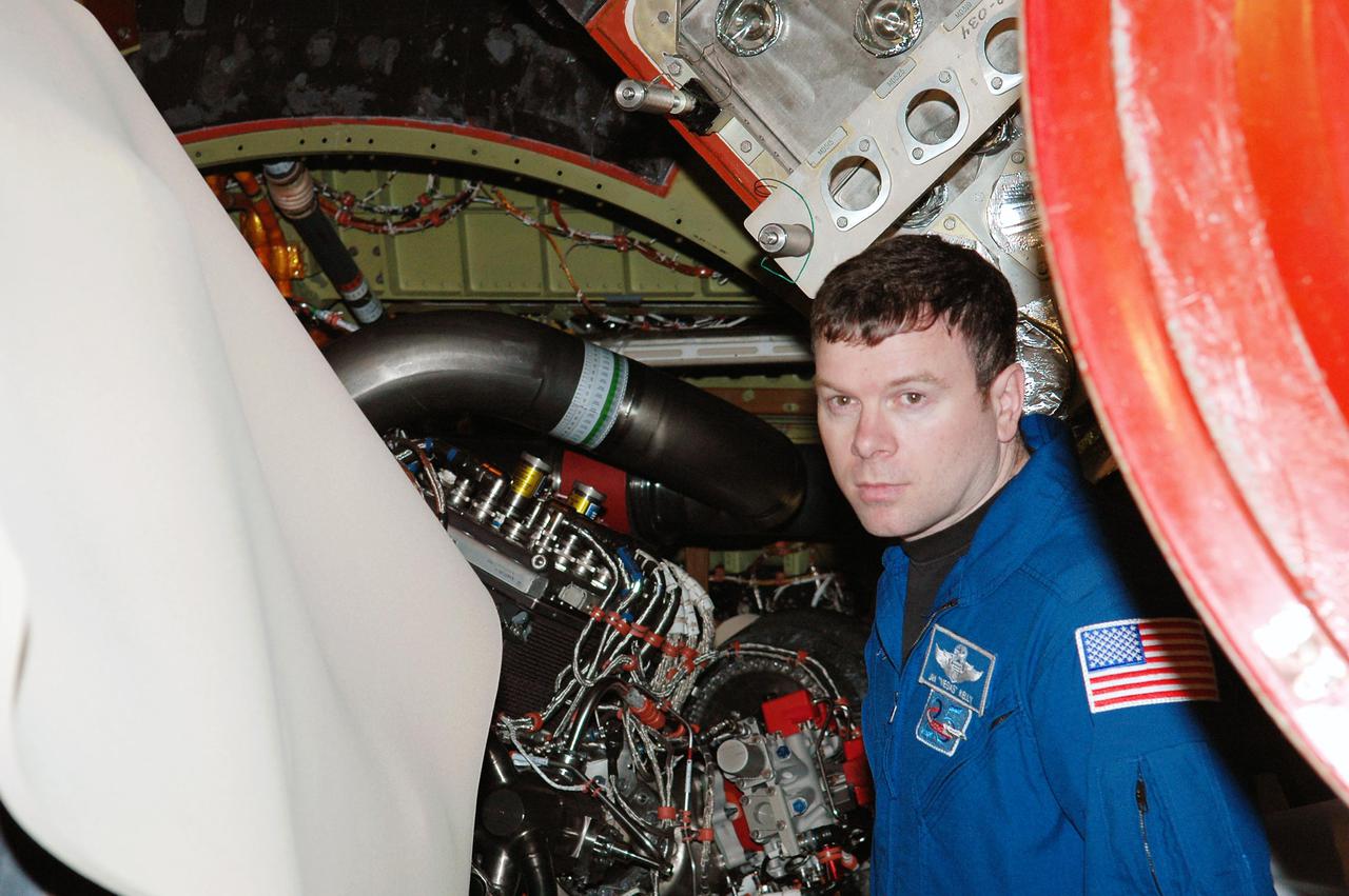 KENNEDY SPACE CENTER, FLA. -  On a visit to Kennedy, STS-114 James Kelly looks closely at an area of an engine on the orbiter Discovery.  The main engines were recently installed.  The designated vehicle for the mission, Discovery is in the Orbiter Processing Facility for launch processing. Discovery is scheduled for a launch planning window of May 12 to June 3, 2005.