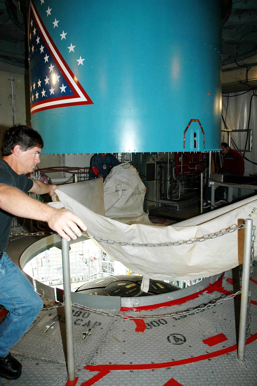 KENNEDY SPACE CENTER, FLA. -  Inside the mobile service tower on Launch Pad 17-B, Cape Canaveral Air Force Station, Fla., a Boeing worker removes a protective cover before the replacement interstage adapter is lowered toward the Boeing Delta II below.  The rocket is the launch vehicle for the Deep Impact spacecraft.  Boeing workers will attach the adapter to the rocket’s center body section.  Later the second stage, which was removed to allow access to the previous adapter, will be reattached. The first adapter was removed after it was found to be faulty during a review of launch vehicle hardware. Launch of Deep Impact is now scheduled no earlier than Jan. 12.