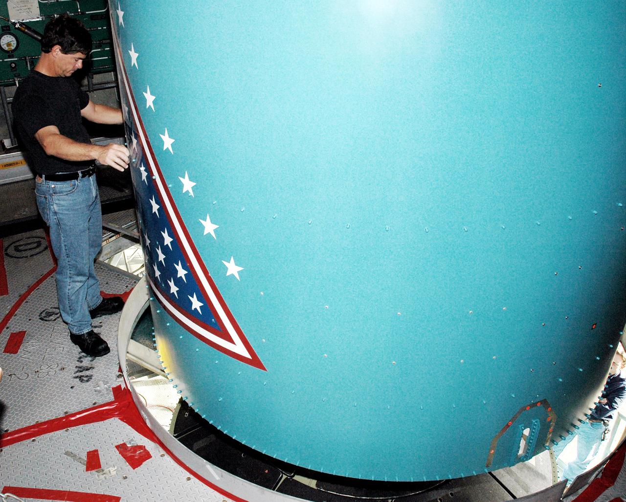 KENNEDY SPACE CENTER, FLA. -  Inside the mobile service tower on Launch Pad 17-B, Cape Canaveral Air Force Station, Fla., a Boeing worker aids in lowering the replacement interstage adapter toward the Boeing Delta II below.  The rocket is the launch vehicle for the Deep Impact spacecraft.  Boeing workers will attach the adapter to the rocket’s center body section.  Later the second stage, which was removed to allow access to the previous adapter, will be reattached. The first adapter was removed after it was found to be faulty during a review of launch vehicle hardware. Launch of Deep Impact is now scheduled no earlier than Jan. 12.