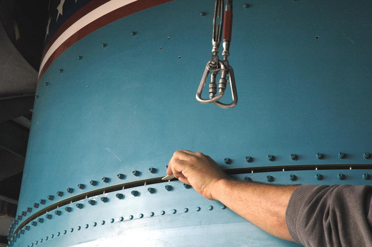KENNEDY SPACE CENTER, FLA. -  Inside the mobile service tower on Launch Pad 17-B, Cape Canaveral Air Force Station, Fla., Boeing technicians work at attaching the replacement interstage adapter to the center body section of the Boeing Delta II rocket.  The rocket is the launch vehicle for the Deep Impact spacecraft.  Boeing workers will attach the adapter to the rocket’s center body section.  Later the second stage, which was removed to allow access to the previous adapter, will be reattached. The first adapter was removed after it was found to be faulty during a review of launch vehicle hardware. Launch of Deep Impact is now scheduled no earlier than Jan. 12.