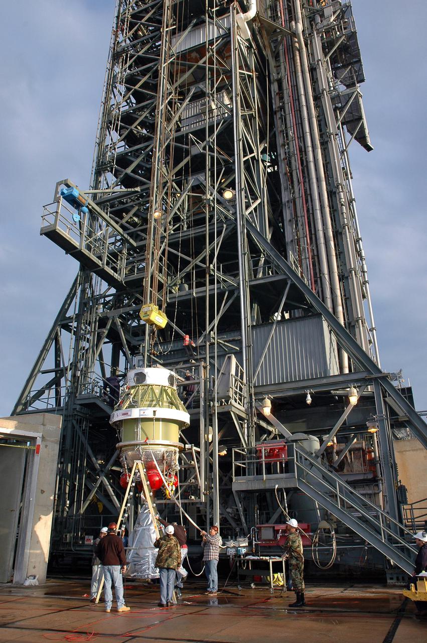 KENNEDY SPACE CENTER, FLA. -  At Launch Pad 17-B, Cape Canaveral Air Force Station, workers remove a protective wrap from the Boeing Delta II second stage.  The component will be lifted up the mobile service tower and reattached to the interstage adapter on the Delta II.  The rocket is the launch vehicle for the Deep Impact spacecraft, scheduled for liftoff no earlier than Jan. 12.  A NASA Discovery mission, Deep Impact will probe beneath the surface of Comet Tempel 1 on July 4, 2005, when the comet is 83 million miles from Earth, and reveal the secrets of its interior.   After releasing a 3- by 3-foot projectile to crash onto the surface, Deep Impact’s flyby spacecraft will collect pictures and data of how the  crater forms, measuring the crater’s depth and diameter, as well as the composition of the interior of the crater and any material thrown out, and determining the changes in natural outgassing produced by the impact.  It will send the data back to Earth through the antennas of the Deep Space Network.