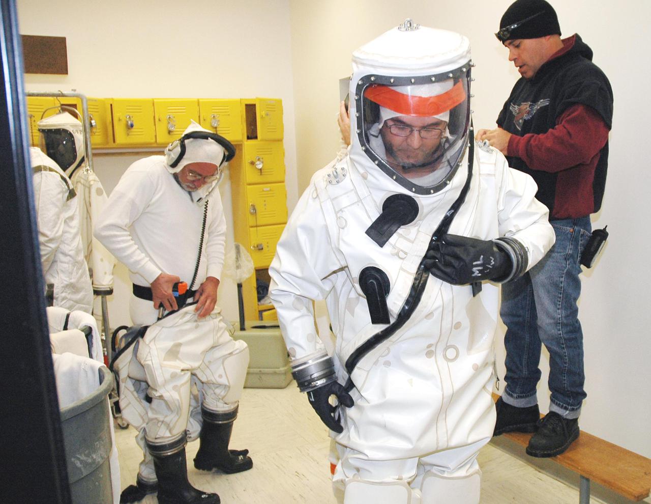 KENNEDY SPACE CENTER, FLA. -  Workers at Astrotech Space Operations in Titusville, Fla., suit up before fueling the Deep Impact spacecraft.  Scheduled for liftoff Jan. 12,  Deep Impact will probe beneath the surface of Comet Tempel 1 on July 4, 2005, when the comet is 83 million miles from Earth, and reveal the secrets of its interior.   After releasing a 3- by 3-foot projectile to crash onto the surface, Deep Impact’s flyby spacecraft will collect pictures and data of how the  crater forms, measuring the crater’s depth and diameter, as well as the composition of the interior of the crater and any material thrown out, and determining the changes in natural outgassing produced by the impact.  It will send the data back to Earth through the antennas of the Deep Space Network.  Deep Impact is a NASA Discovery mission.