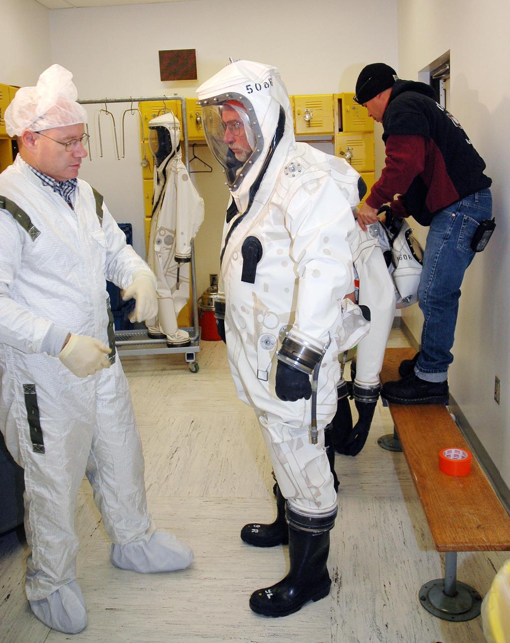 KENNEDY SPACE CENTER, FLA. -  Workers at Astrotech Space Operations in Titusville, Fla., suit up before fueling the Deep Impact spacecraft.  Scheduled for liftoff Jan. 12,  Deep Impact will probe beneath the surface of Comet Tempel 1 on July 4, 2005, when the comet is 83 million miles from Earth, and reveal the secrets of its interior.   After releasing a 3- by 3-foot projectile to crash onto the surface, Deep Impact’s flyby spacecraft will collect pictures and data of how the  crater forms, measuring the crater’s depth and diameter, as well as the composition of the interior of the crater and any material thrown out, and determining the changes in natural outgassing produced by the impact.  It will send the data back to Earth through the antennas of the Deep Space Network.  Deep Impact is a NASA Discovery mission.